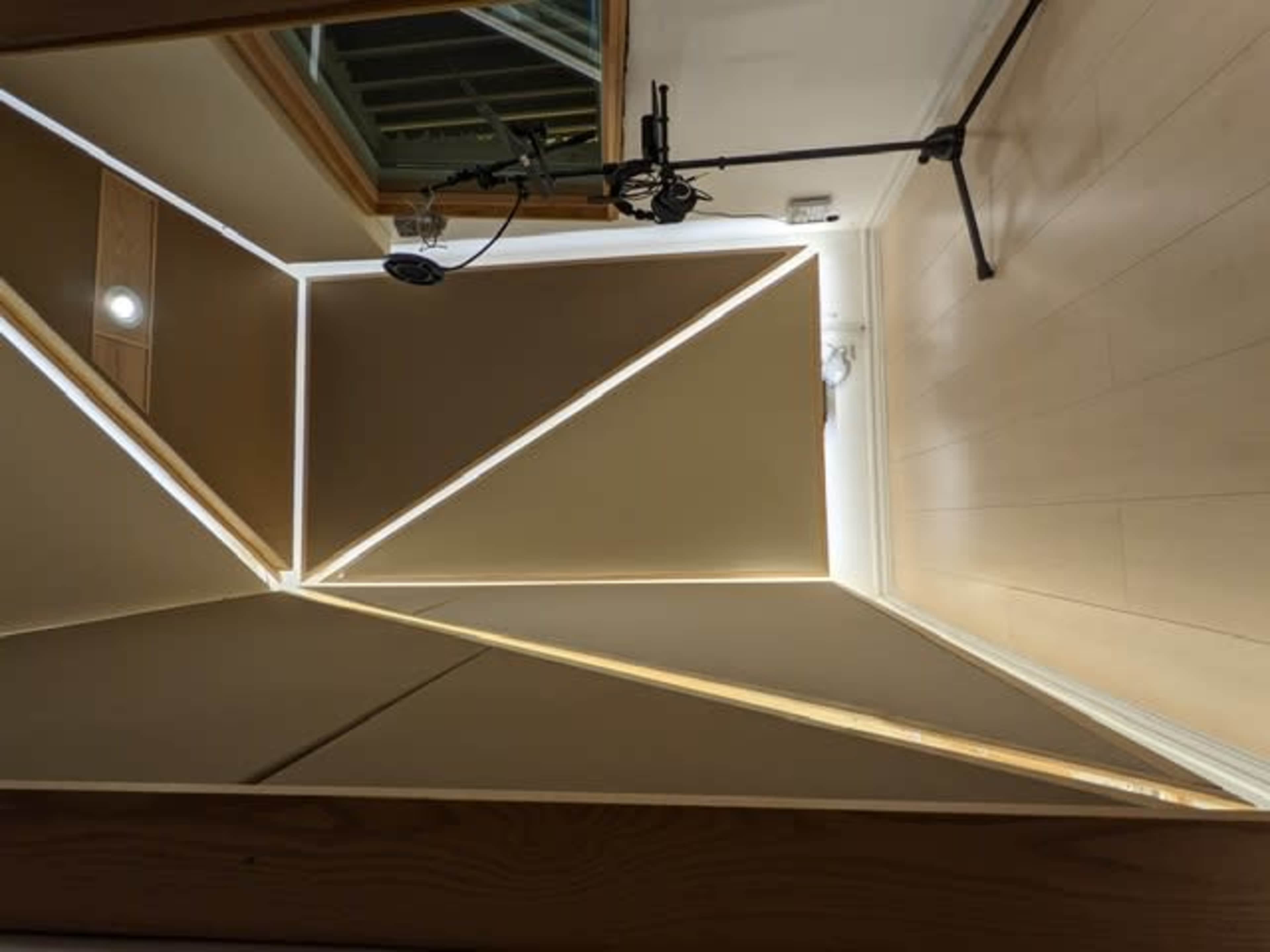 The ceiling and walls of a room with geometric wood paneling and soft lighting.