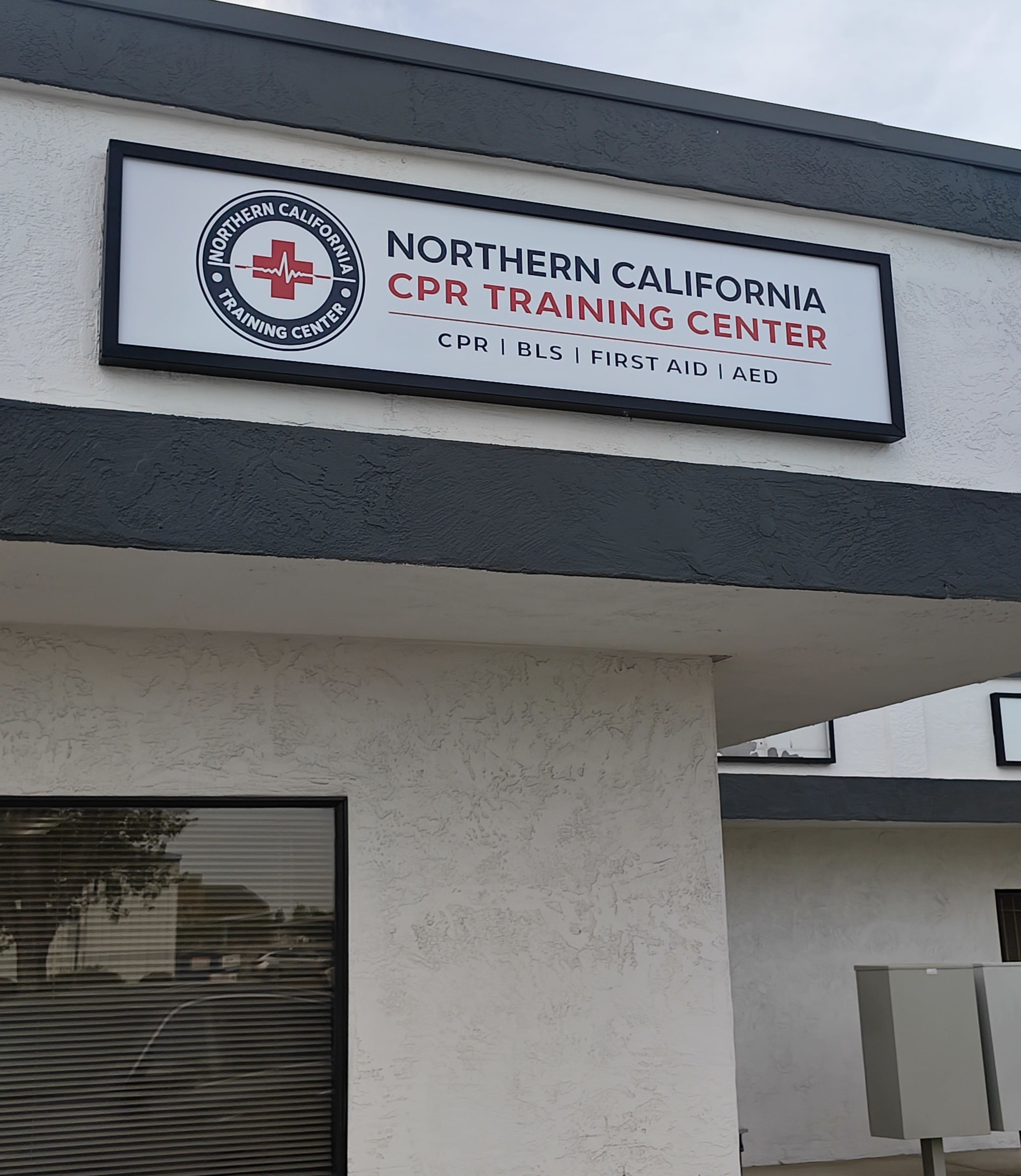 The image shows a sign for the Northern California CPR Training Center, displaying information about CPR, BLS, First Aid, and AED training.