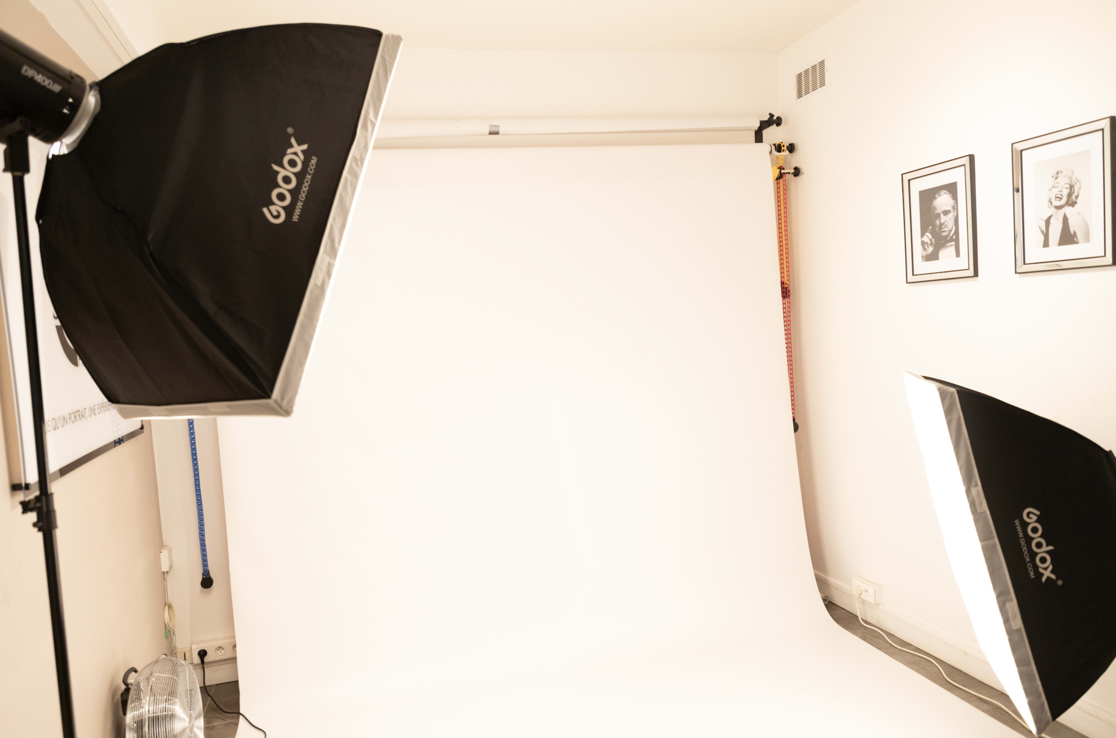 A photography studio with two Godox light setups and a plain white backdrop.