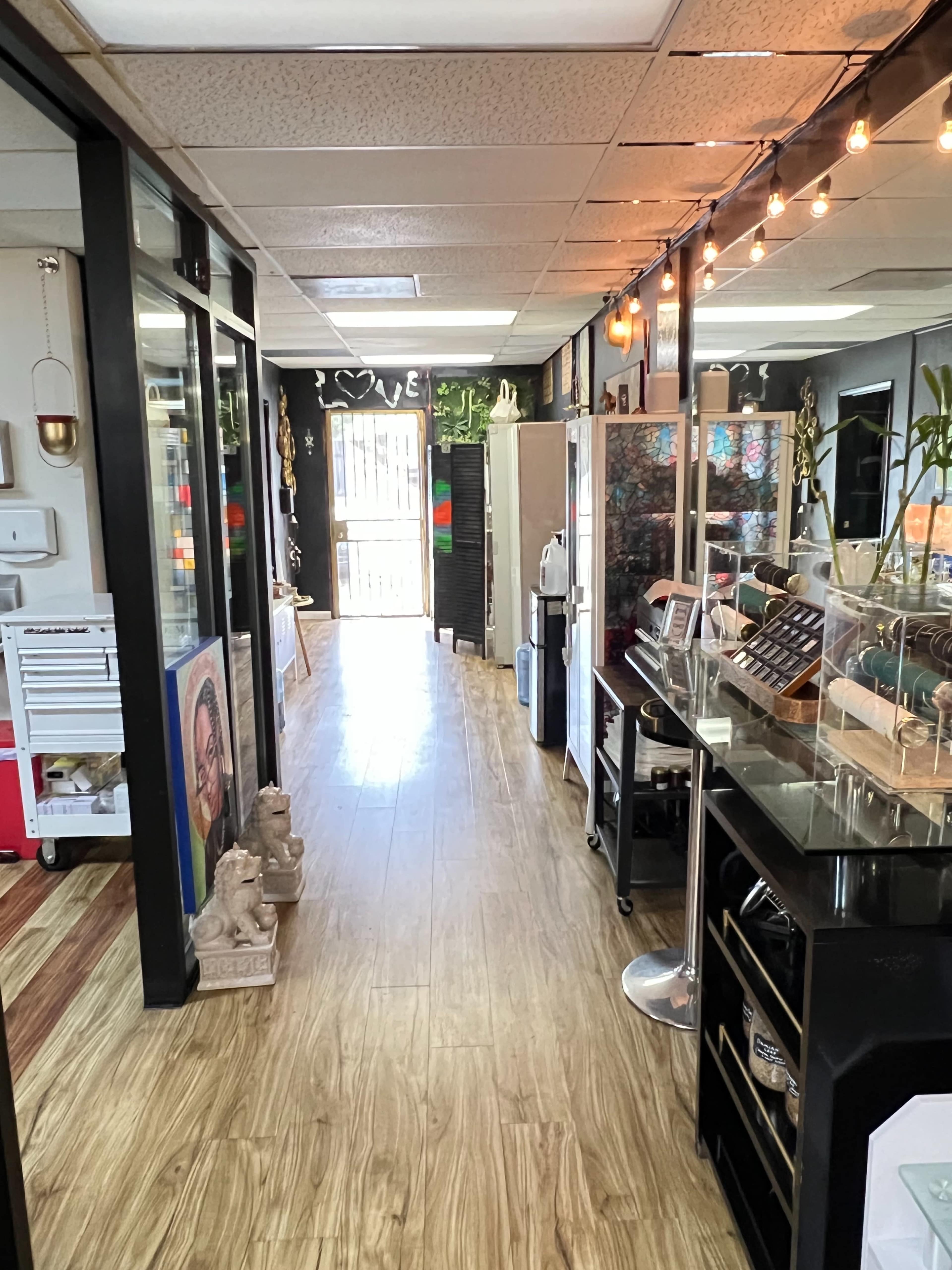 The image shows a long, well-lit hallway lined with artwork and display cases, leading to an outdoor area.