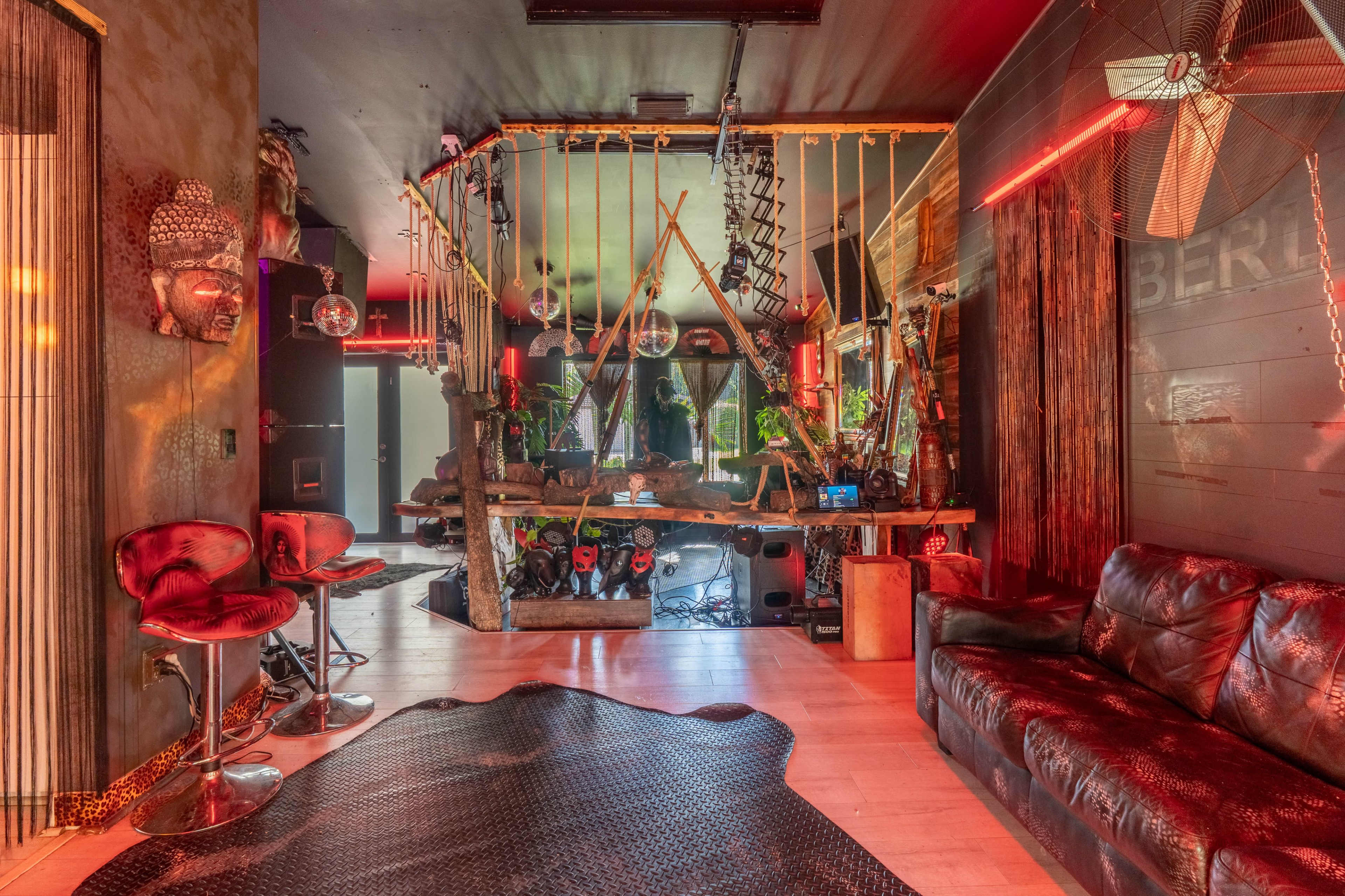 The image shows a creatively designed interior space featuring a mix of modern furniture, hanging elements, and ambient lighting.