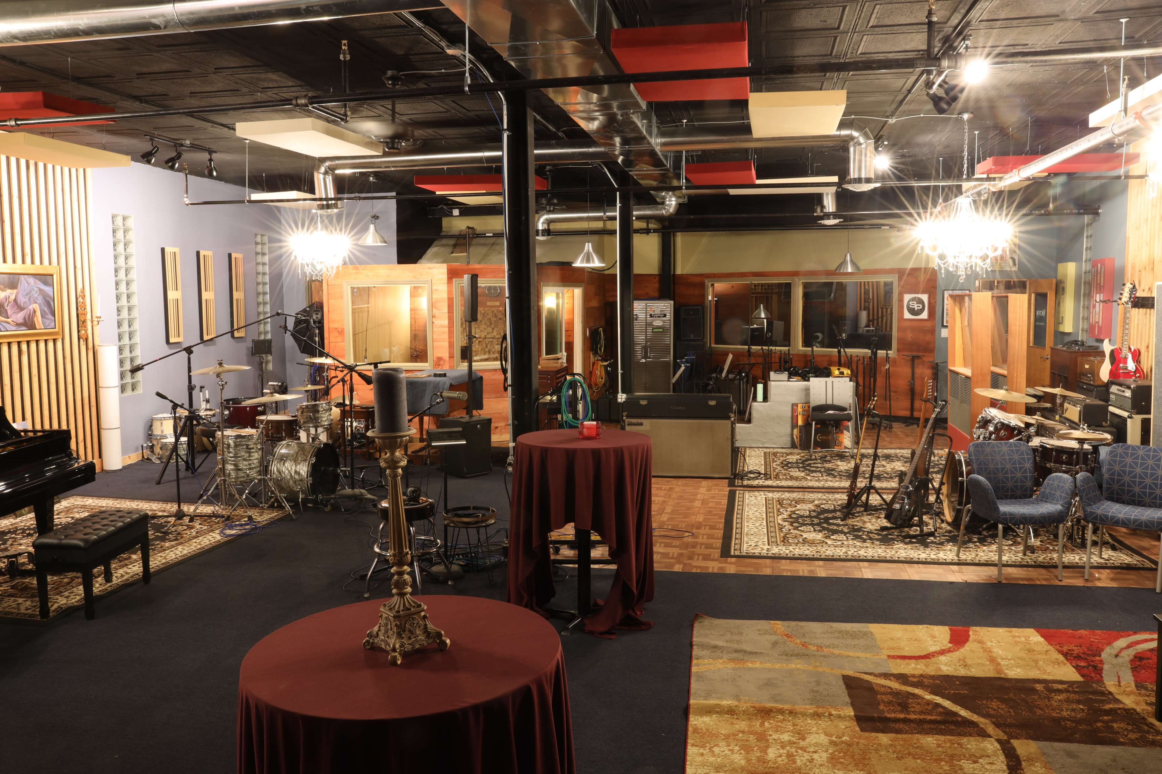 A spacious music recording studio with various instruments, soundproof rooms, and seating areas.