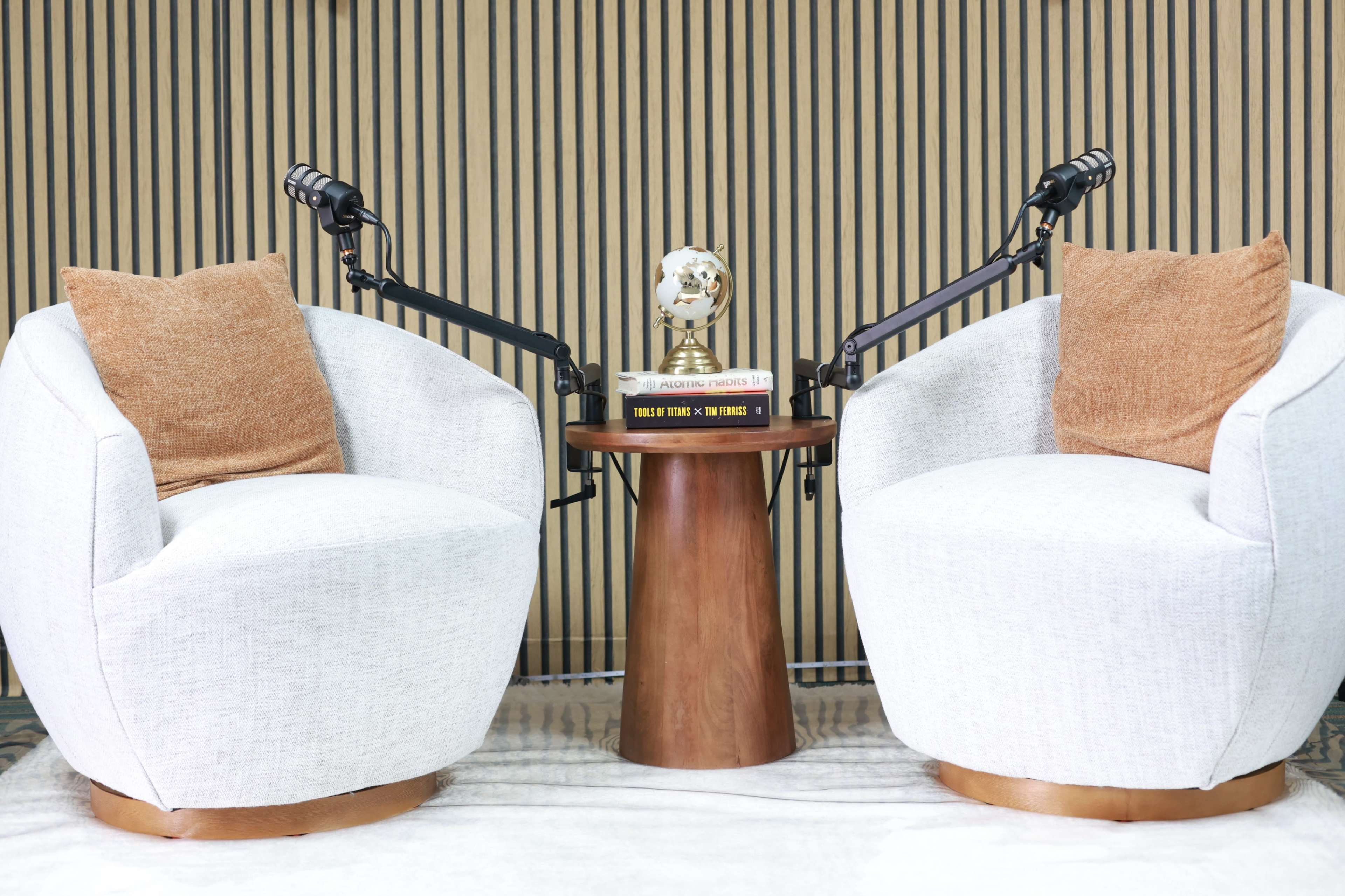 The image shows two white, upholstered chairs facing each other, accompanied by a small wooden table with a decorative globe and books in between them.
