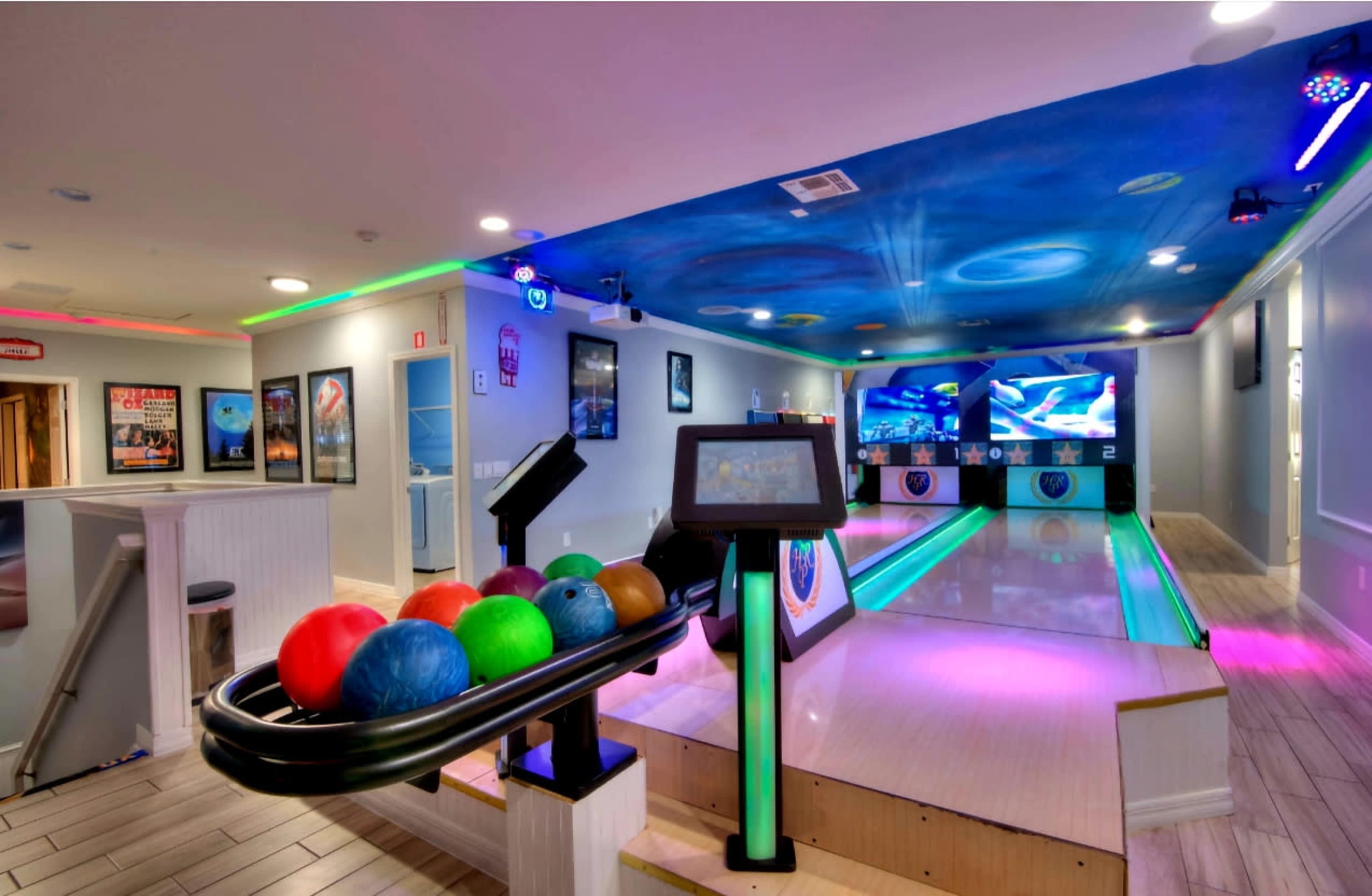 A modern bowling alley with colorful lights, a ball return system holding several bowling balls, and a polished lane in the background.