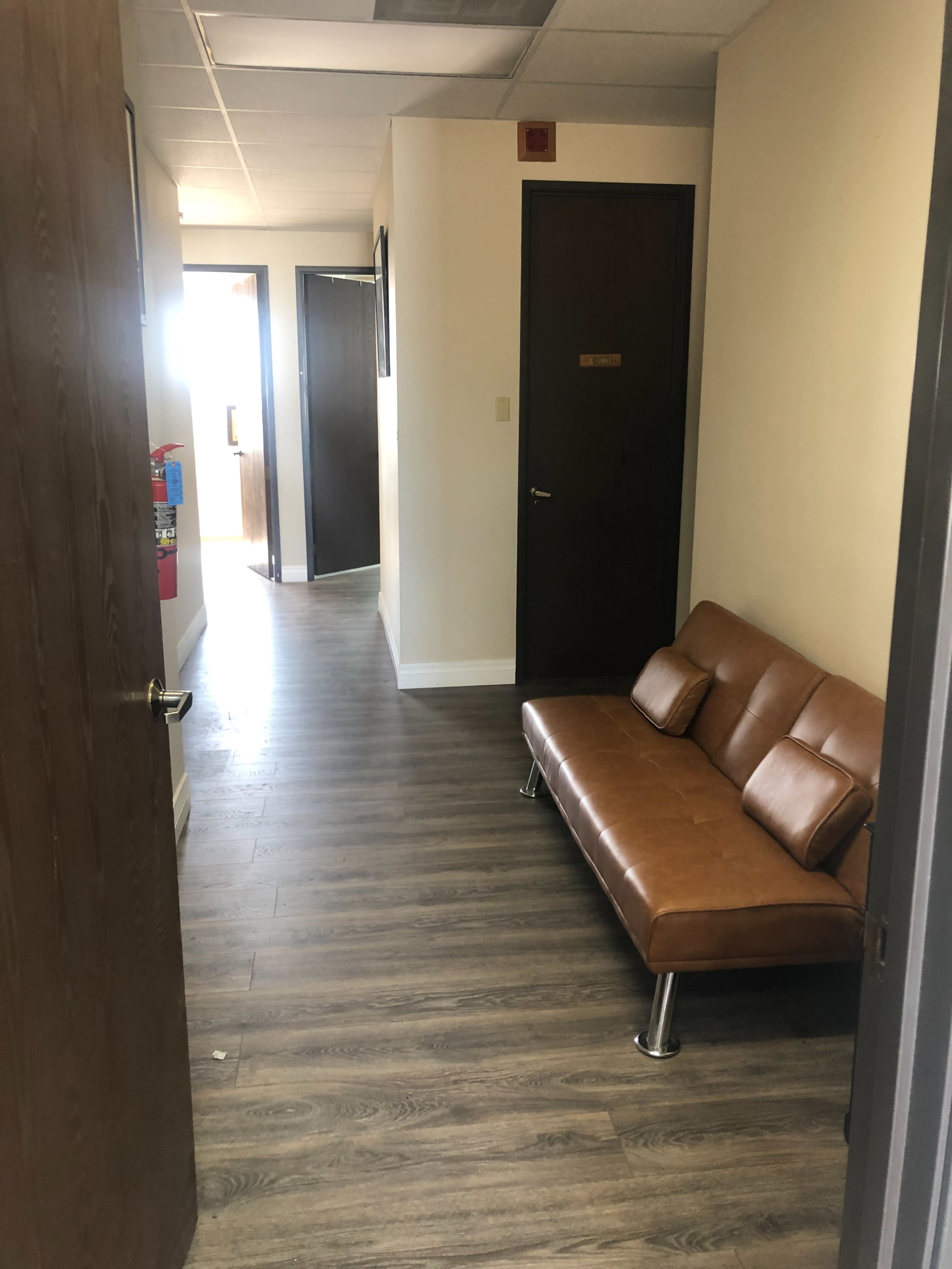 A hallway features a brown leather sofa and doors leading to other rooms.
