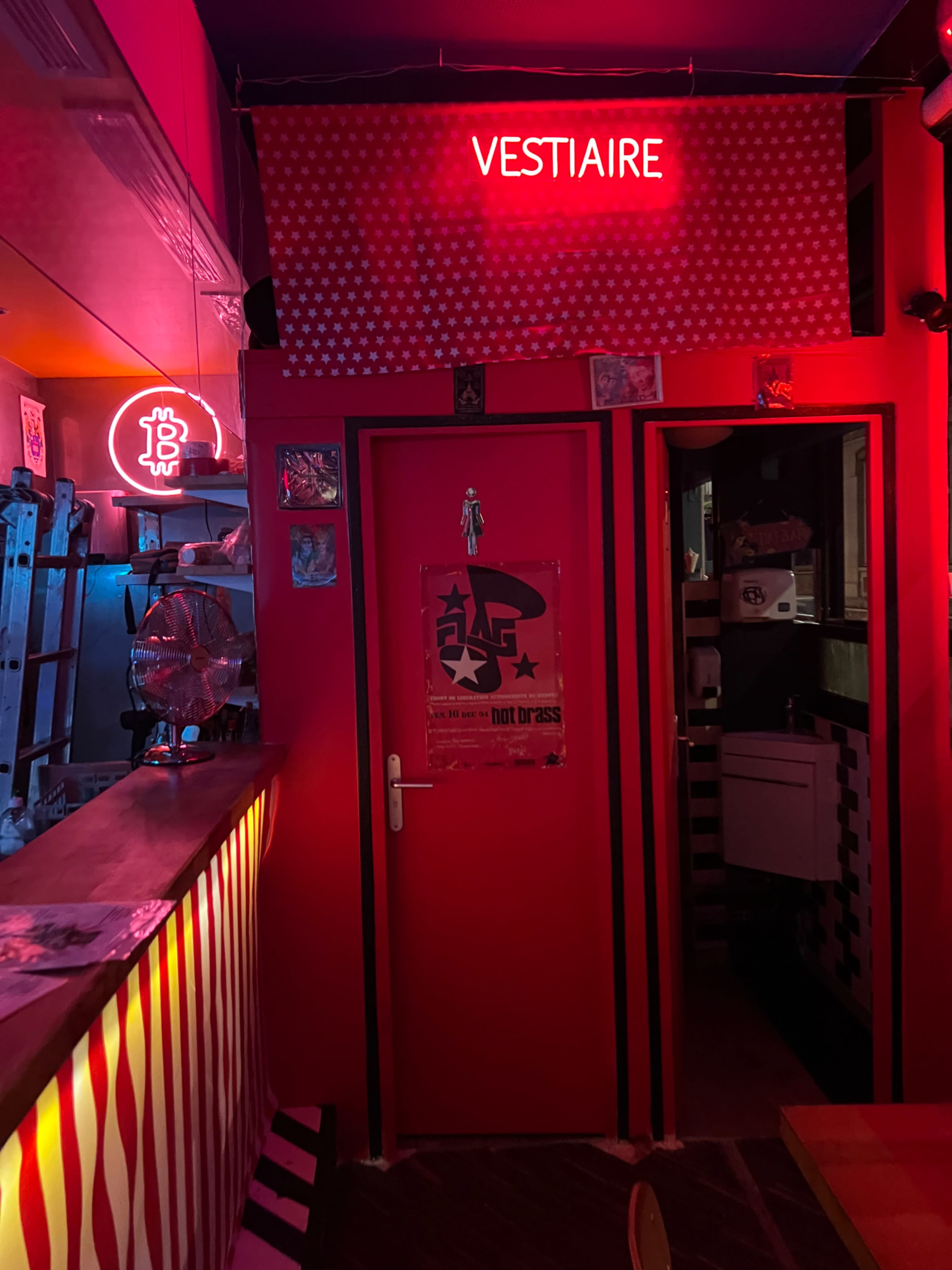 The image features a brightly lit hallway leading to a door labeled "VESTIAIRE," with colorful neon lights and vibrant interior decor.