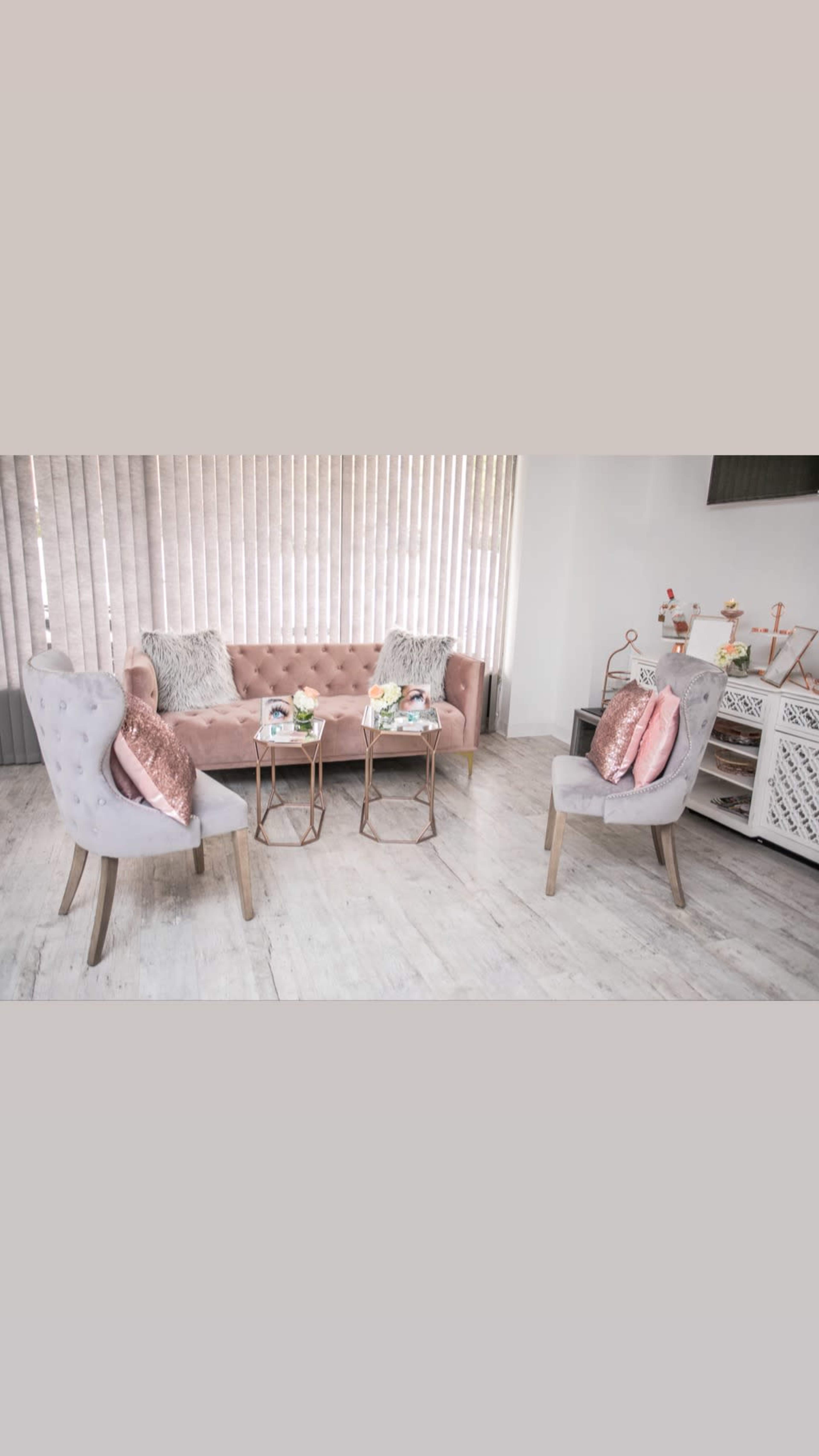 A modern, elegantly furnished sitting area with a pink tufted sofa and two matching armchairs arranged around small side tables.