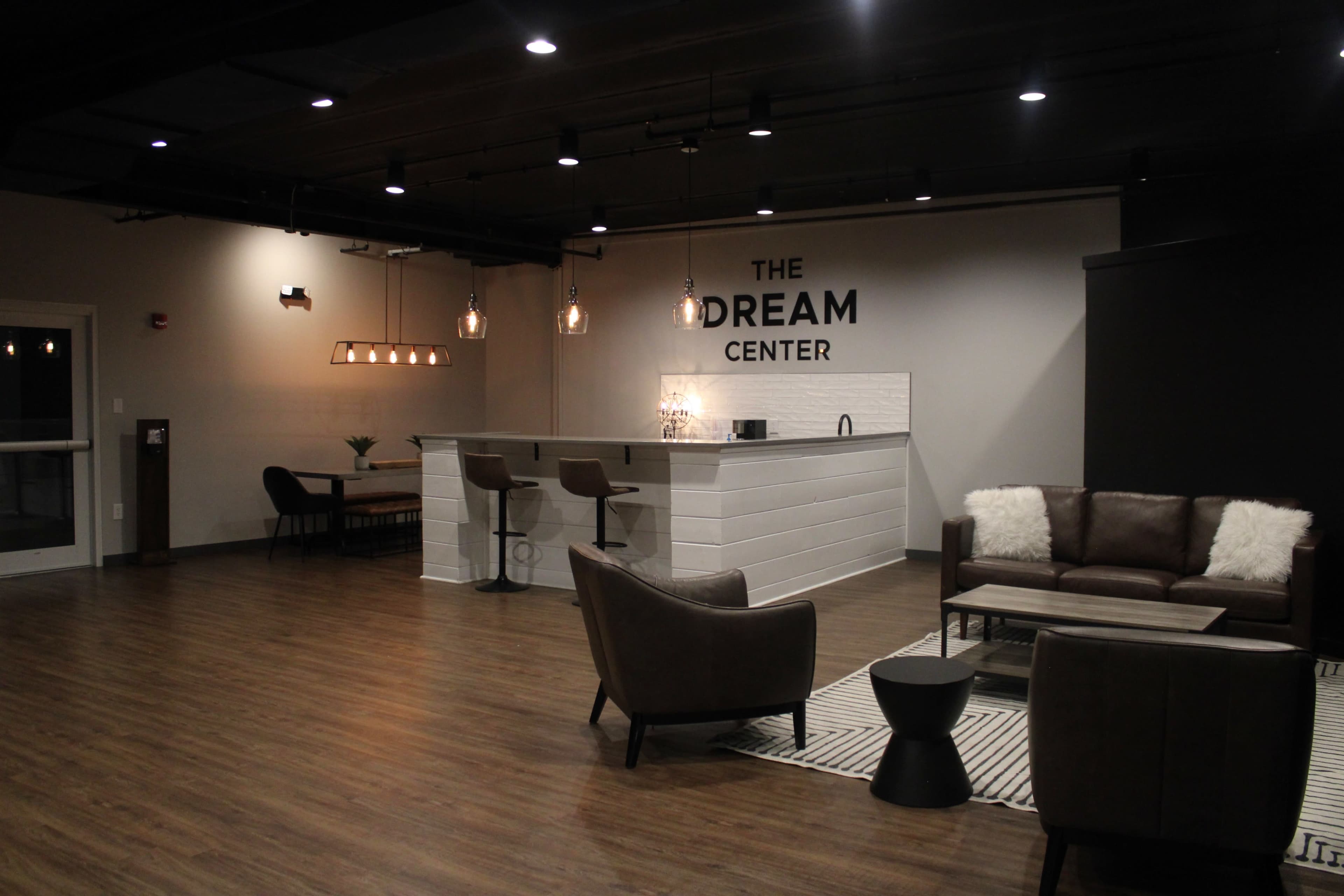 A modern interior space featuring a bar area with stools, seating arrangements, and decorative lighting.