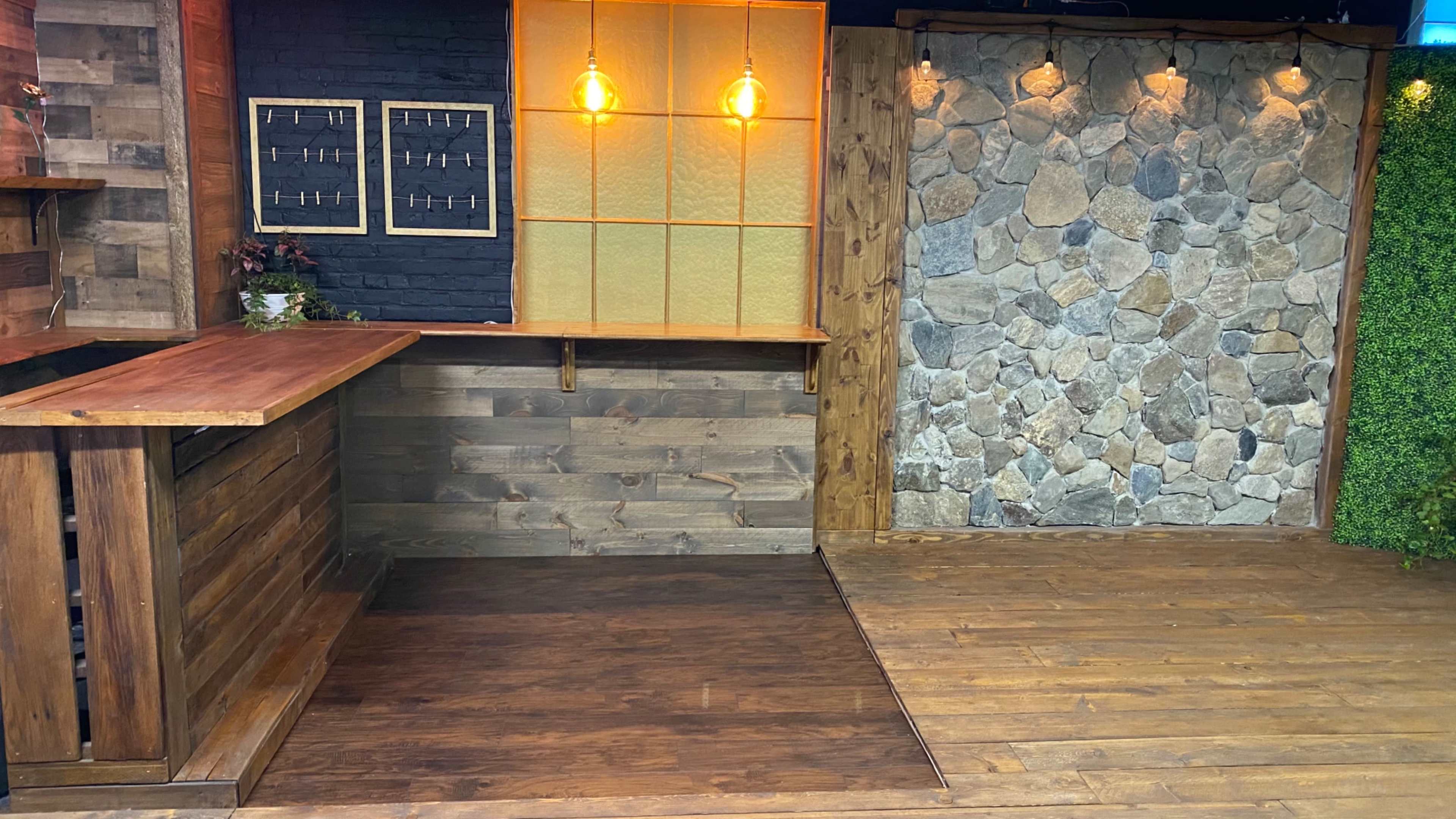A rustic interior space with wooden panels, a stone wall, and warm pendant lighting.