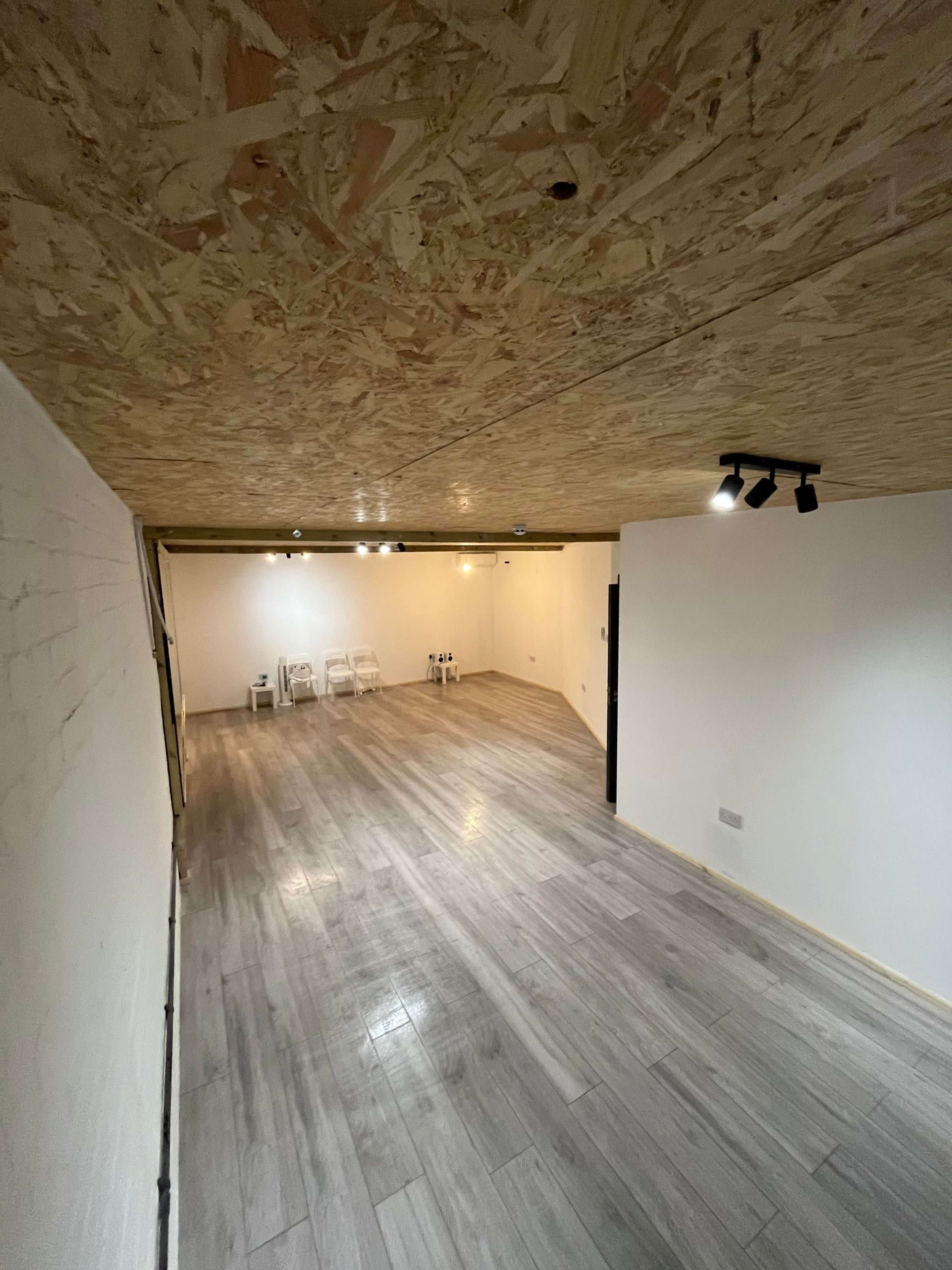 An empty interior space with a wooden ceiling, light-colored flooring, and white walls.