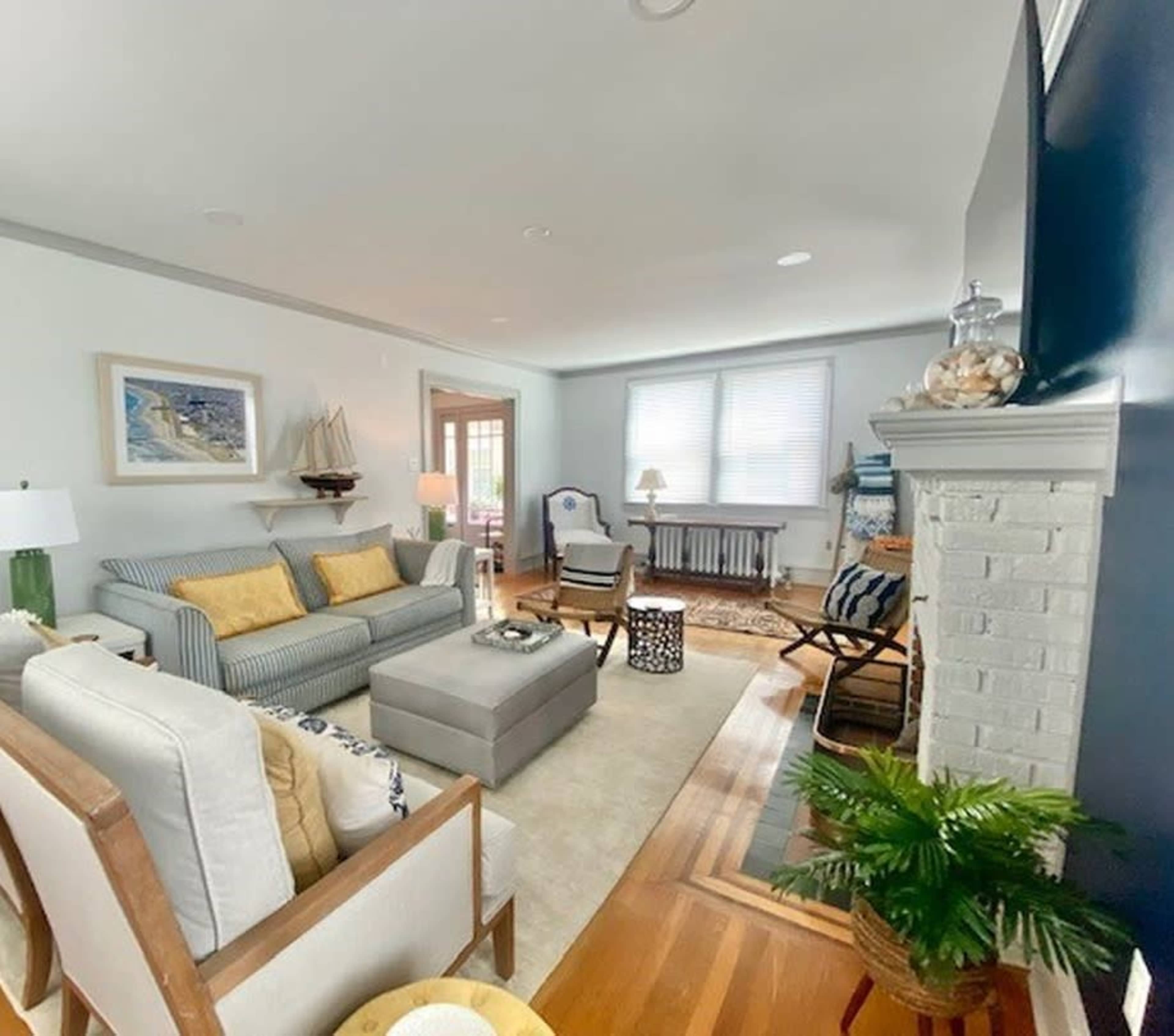 The image shows a well-lit living room with a striped sofa, a coffee table, and a fireplace, featuring a mix of furniture and decorative elements.