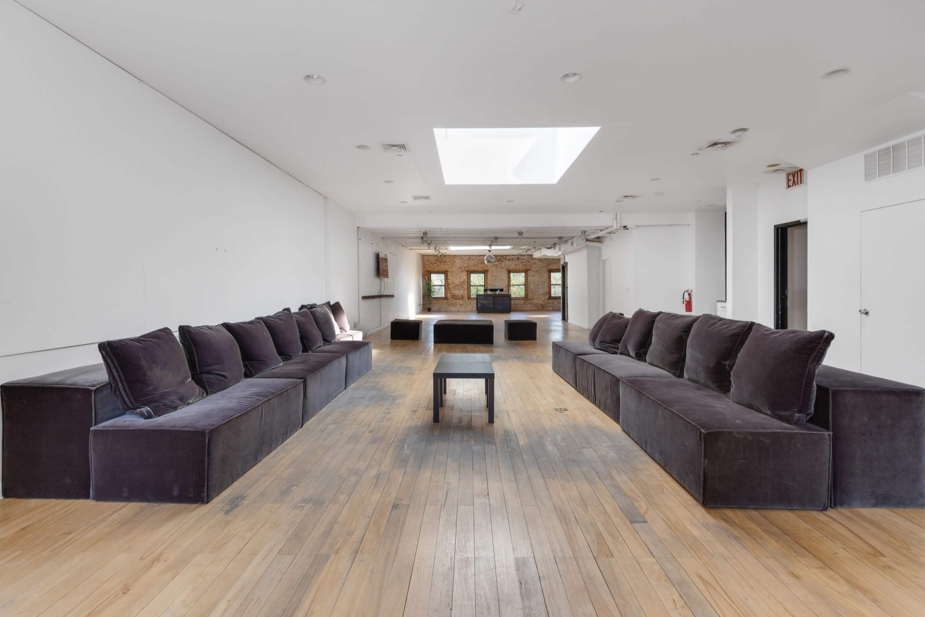 A spacious room with two long, dark sofas arranged facing each other and a small table in the center.