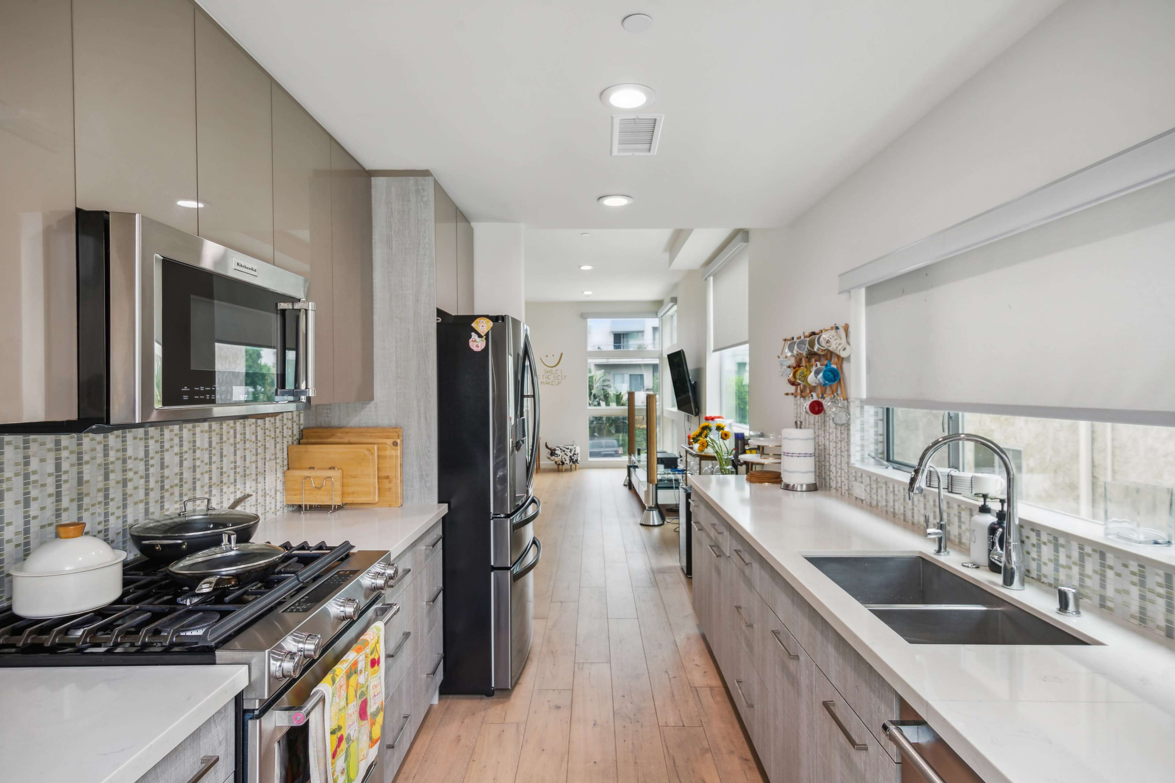 A modern kitchen featuring stainless steel appliances, white countertops, and a window with a view of an adjacent room.