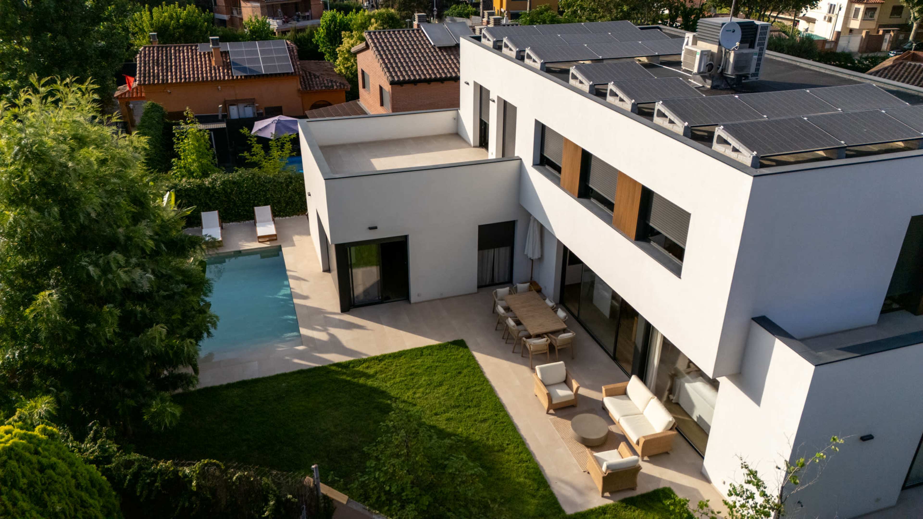 The image shows a modern house with solar panels on the roof, a swimming pool, and a landscaped yard.