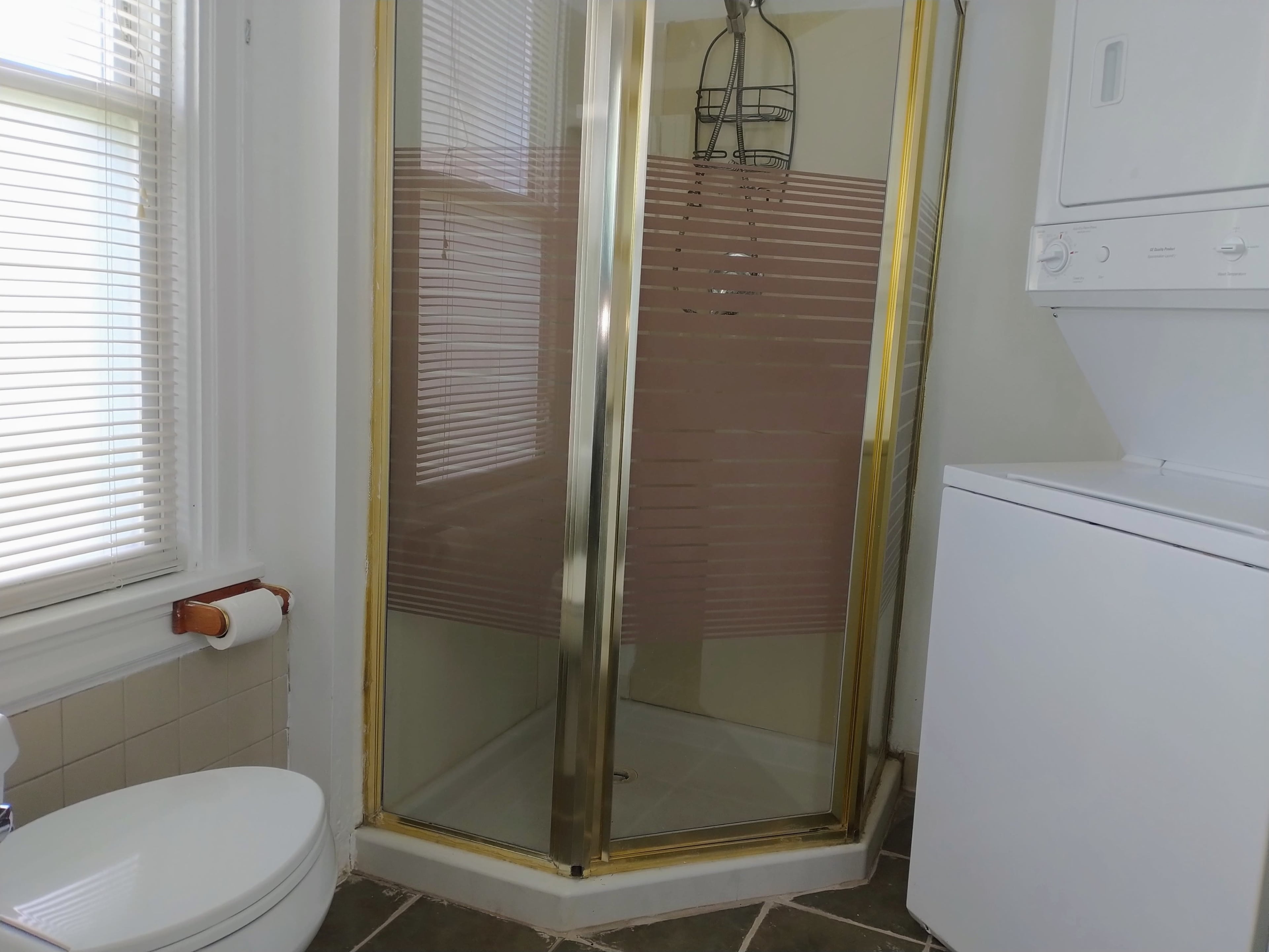 A bathroom featuring a shower stall with sliding doors, a toilet, and a stacked washer and dryer.