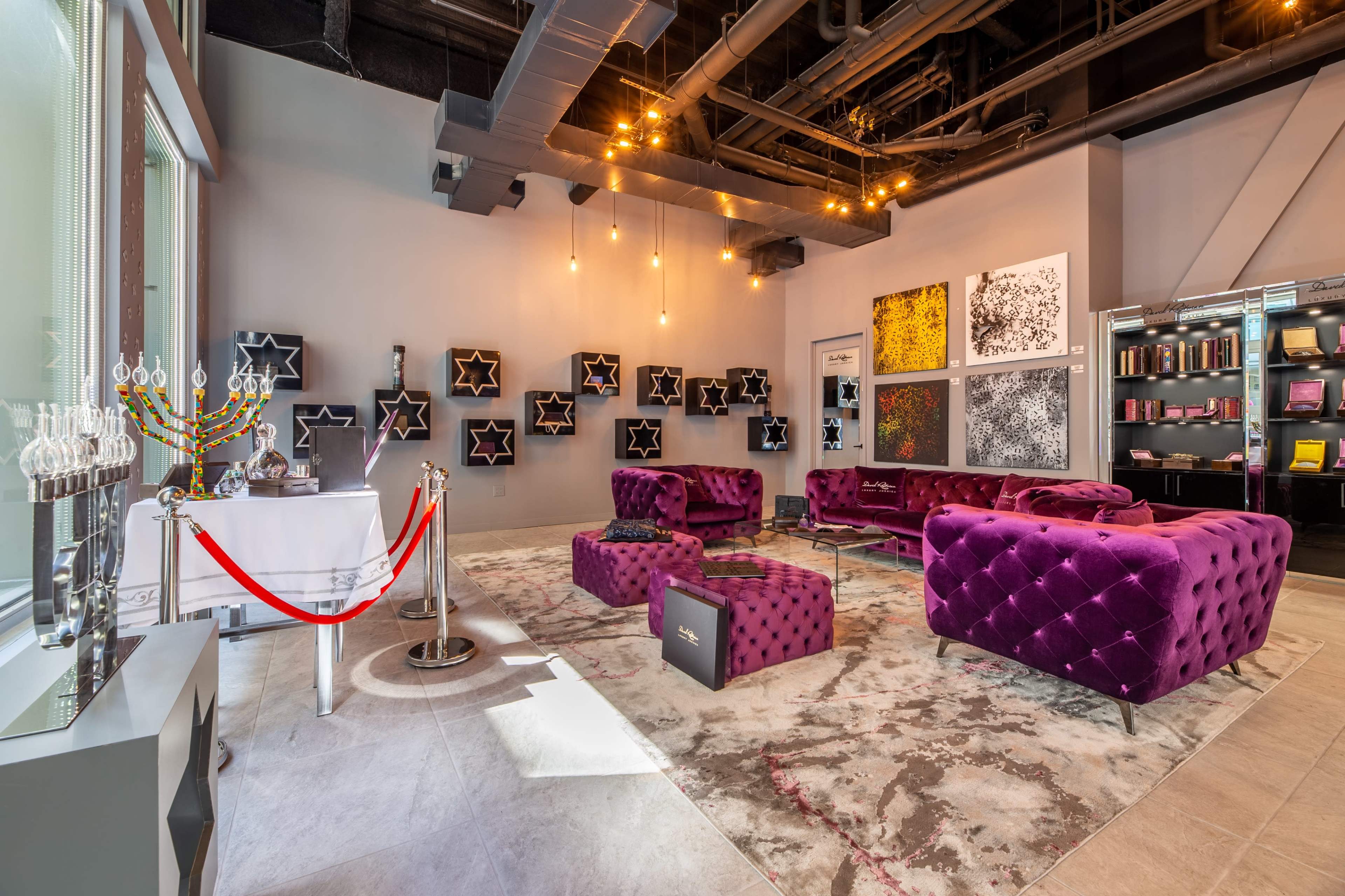 The scene shows a modern interior with purple velvet seating, artwork on the walls, and a display area featuring various products.