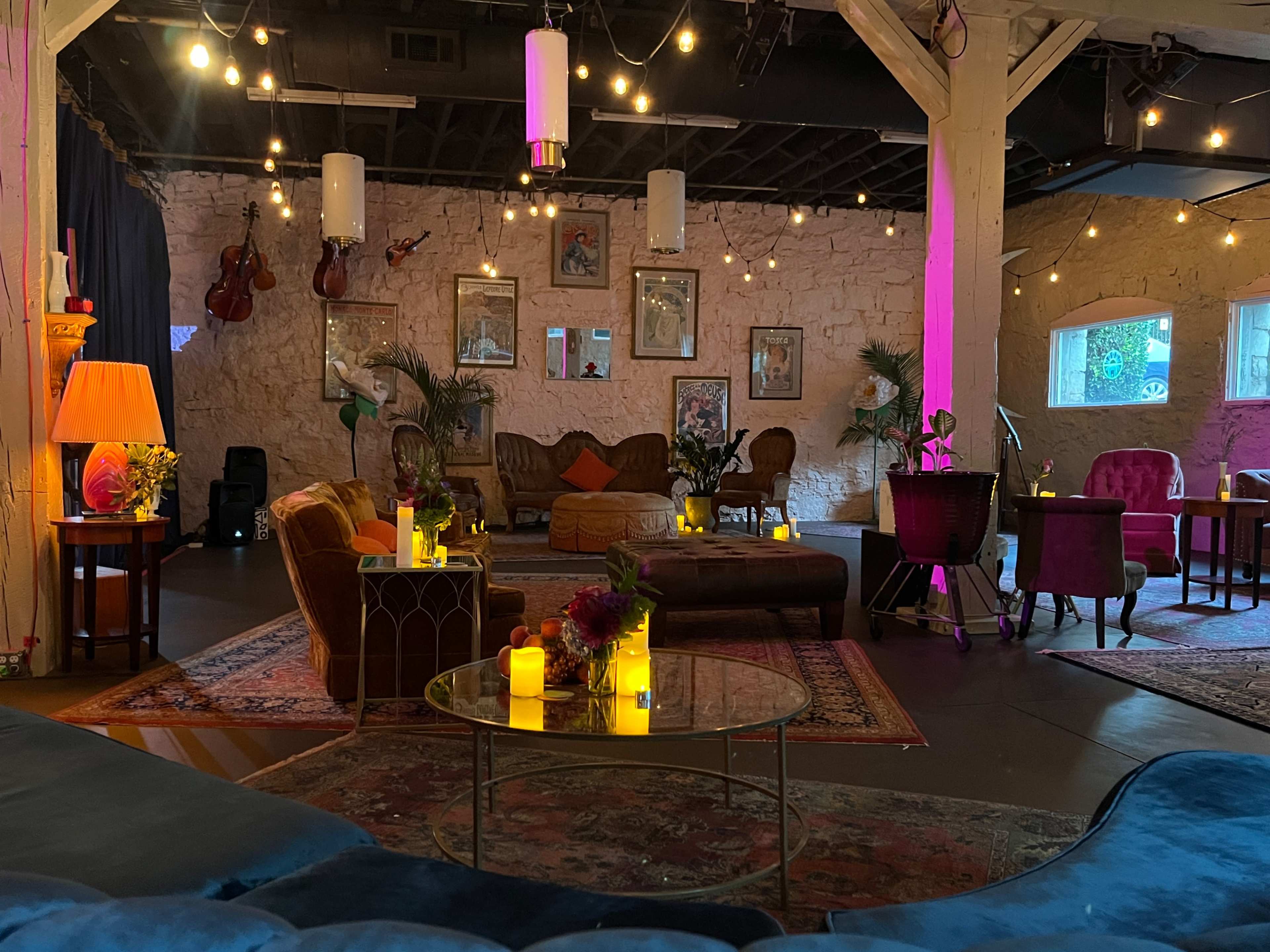 The image shows a cozy lounge area with vintage furniture, soft lighting, and decorative plants, creating an inviting atmosphere.