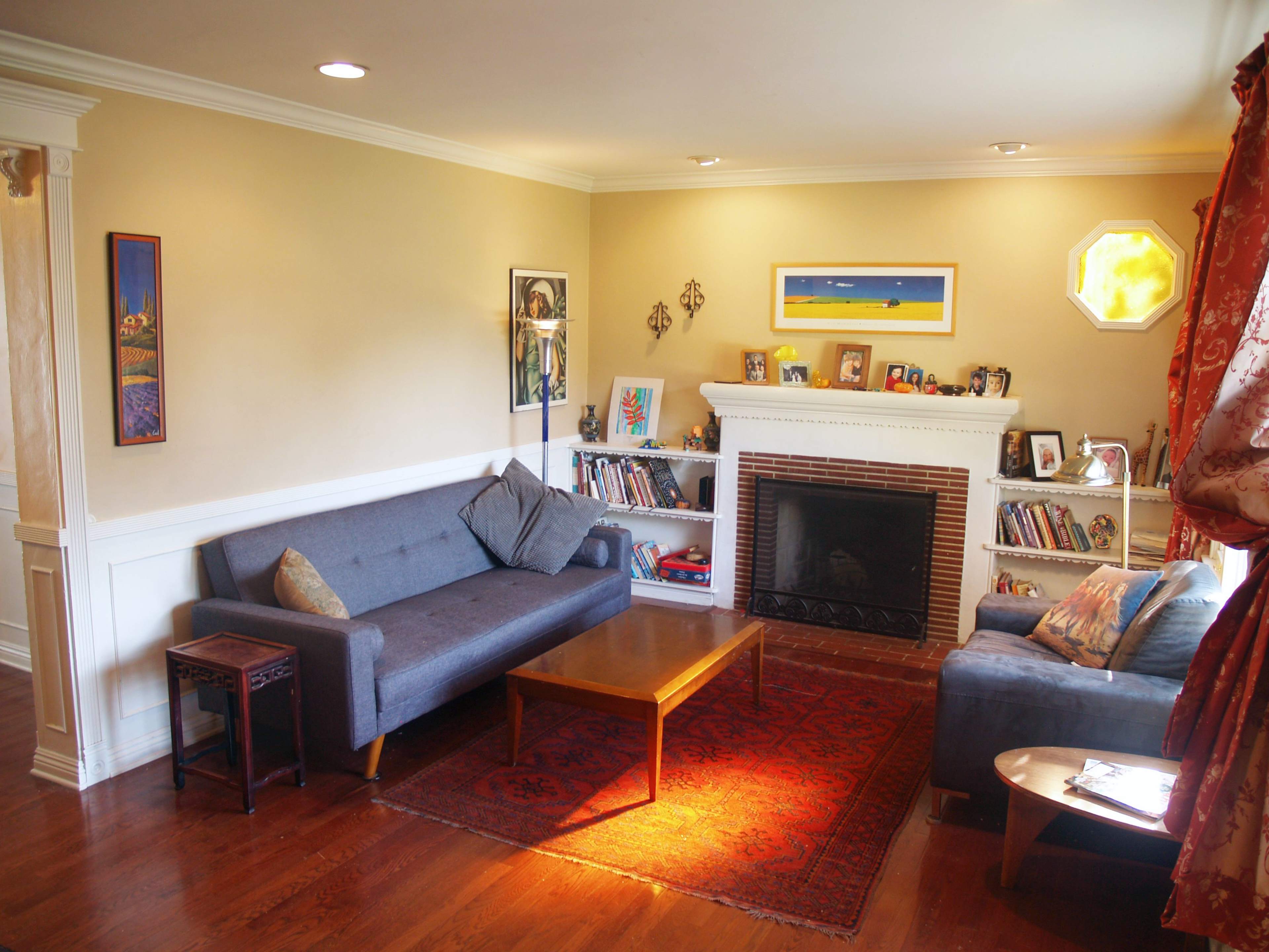 A cozy living room with two sofas, a coffee table, a fireplace, and bookshelves against the walls.