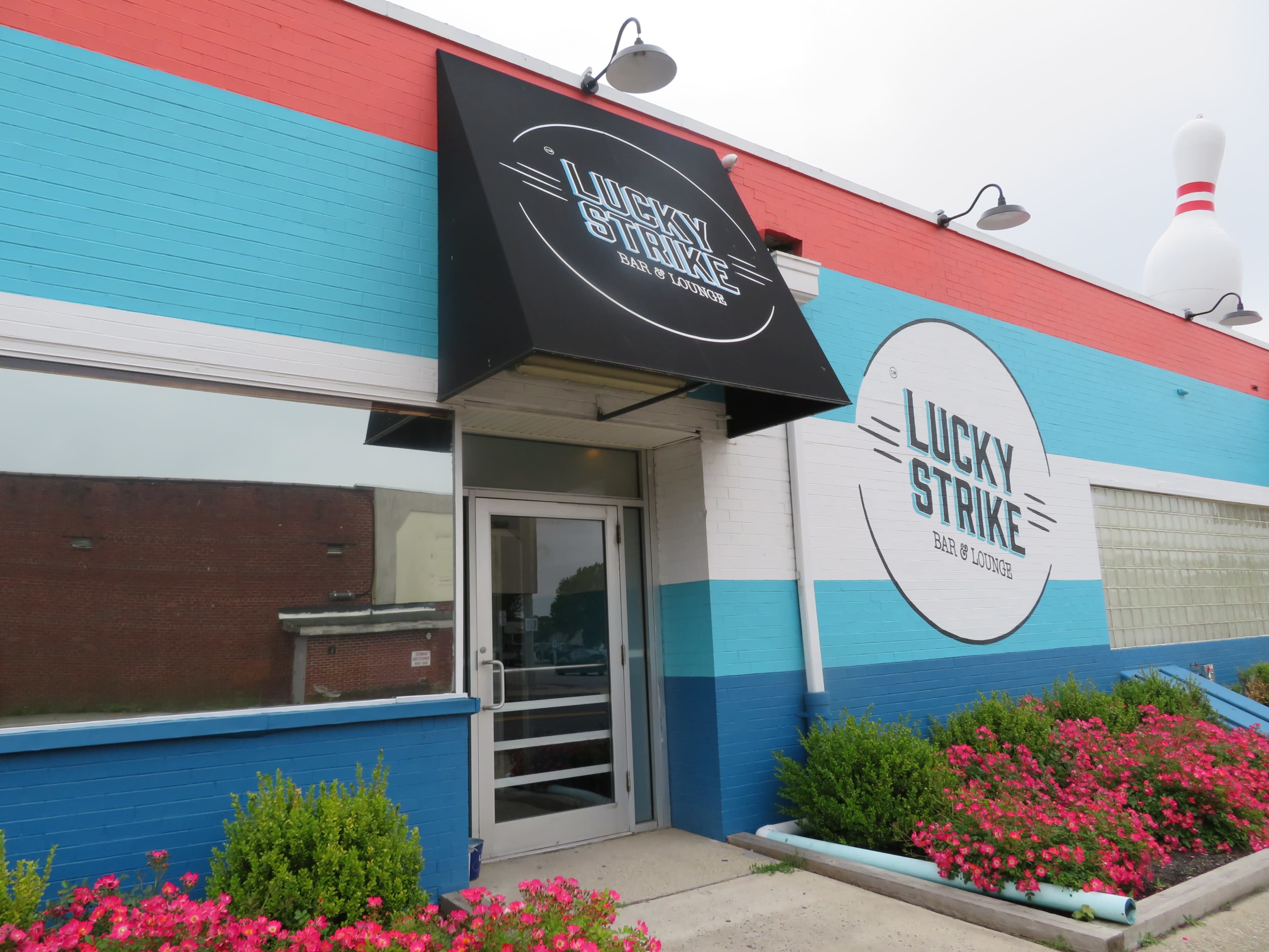 The image shows the entrance of a bowling alley and bar named "Lucky Strike," featuring a colorful blue and red exterior with a prominent sign.