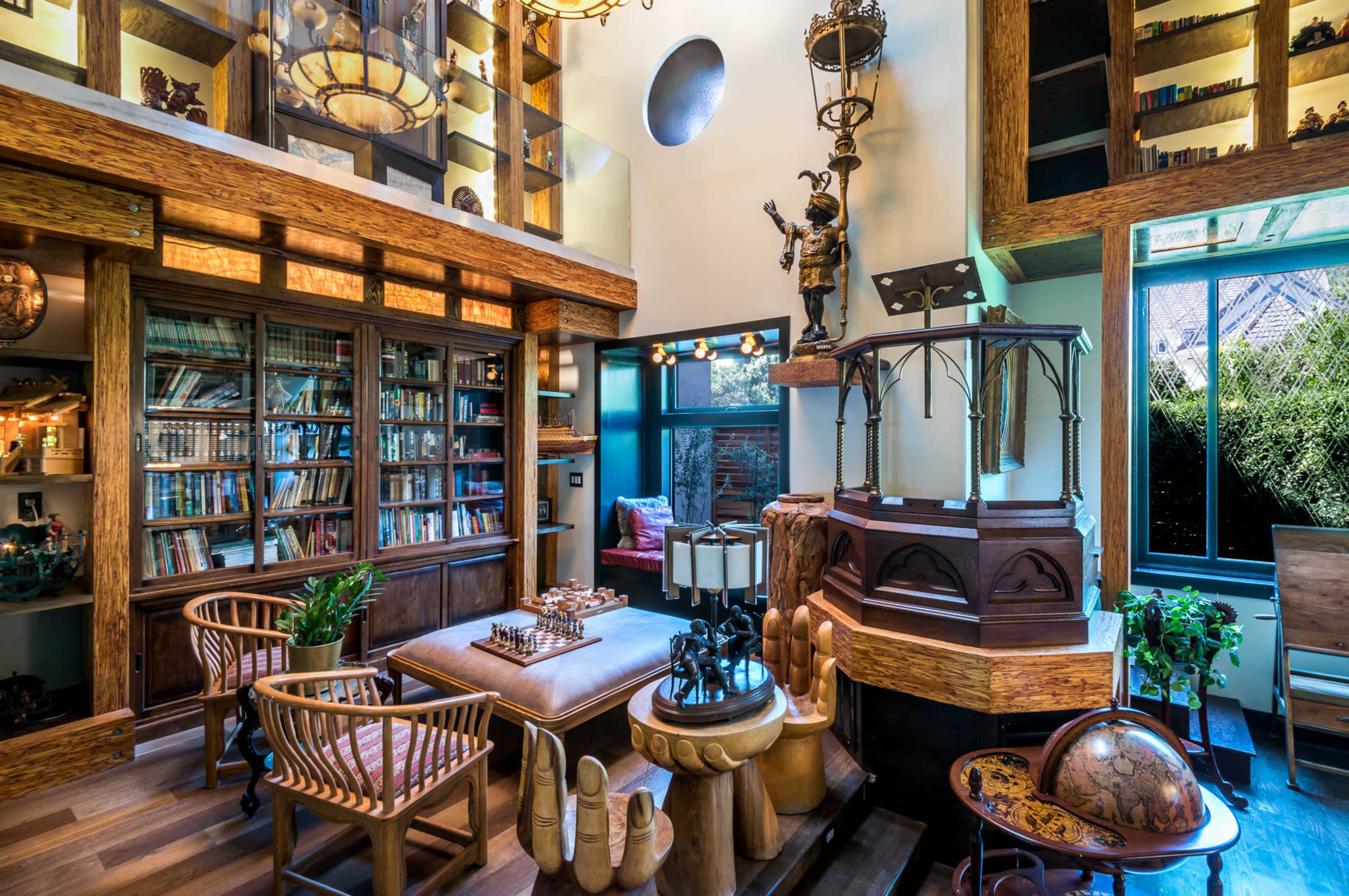 A cozy interior of a well-furnished library with wooden shelves filled with books, various decorative items, and comfortable seating arrangements.