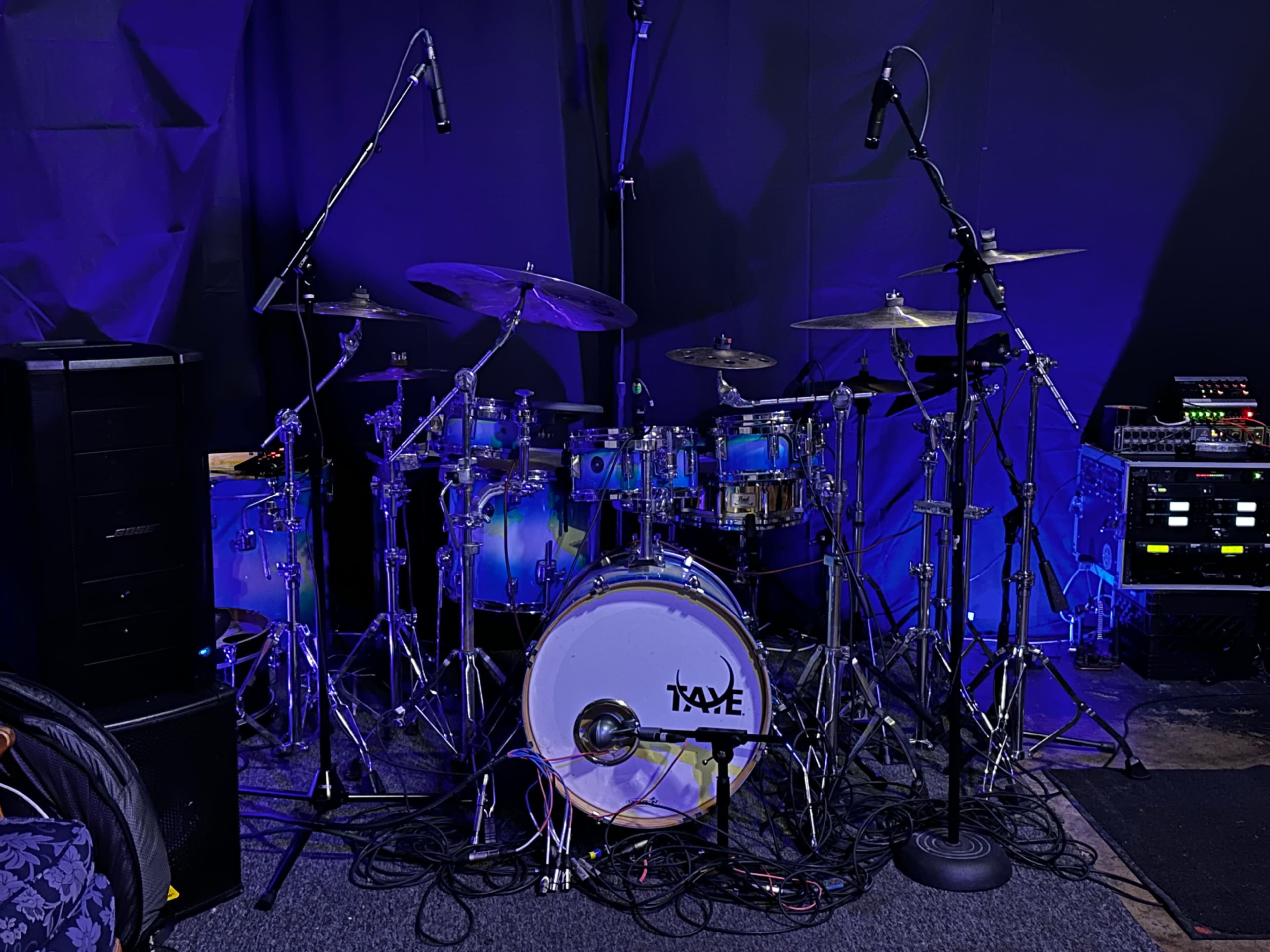 A drum set with microphones is set up in a dimly lit recording studio.