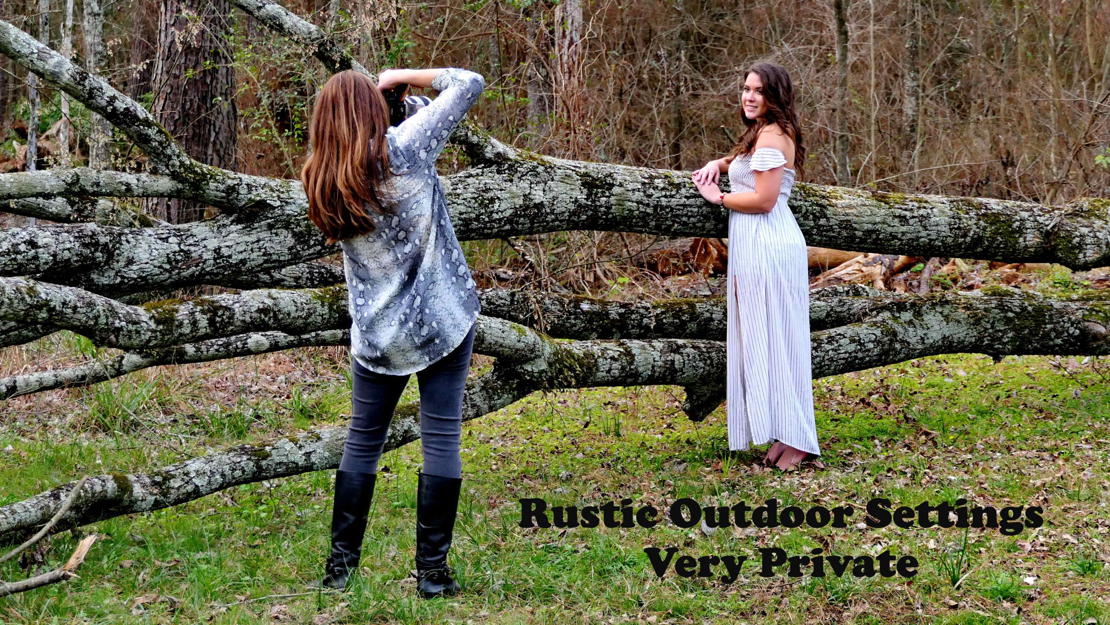 A photographer captures an image of a model posing in a white dress near a fallen log in a wooded area.