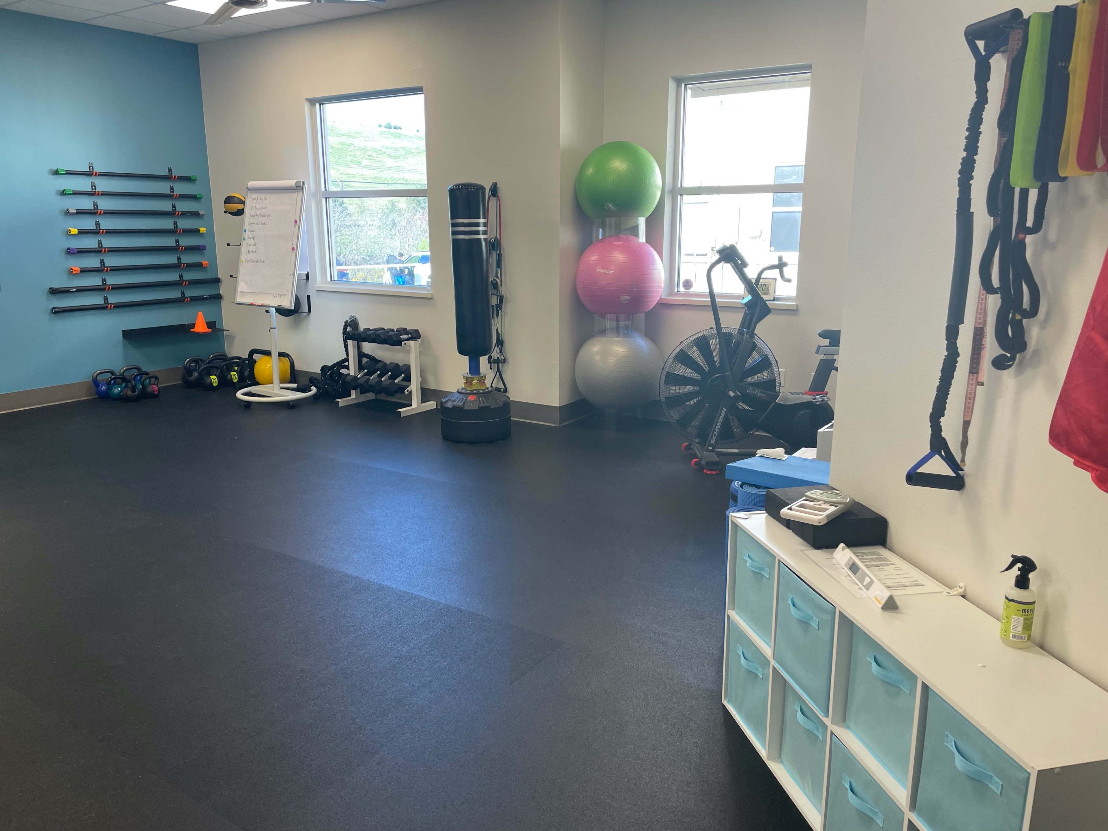 A fitness training room equipped with various exercise equipment, including weights, resistance bands, exercise balls, and a stationary bike.