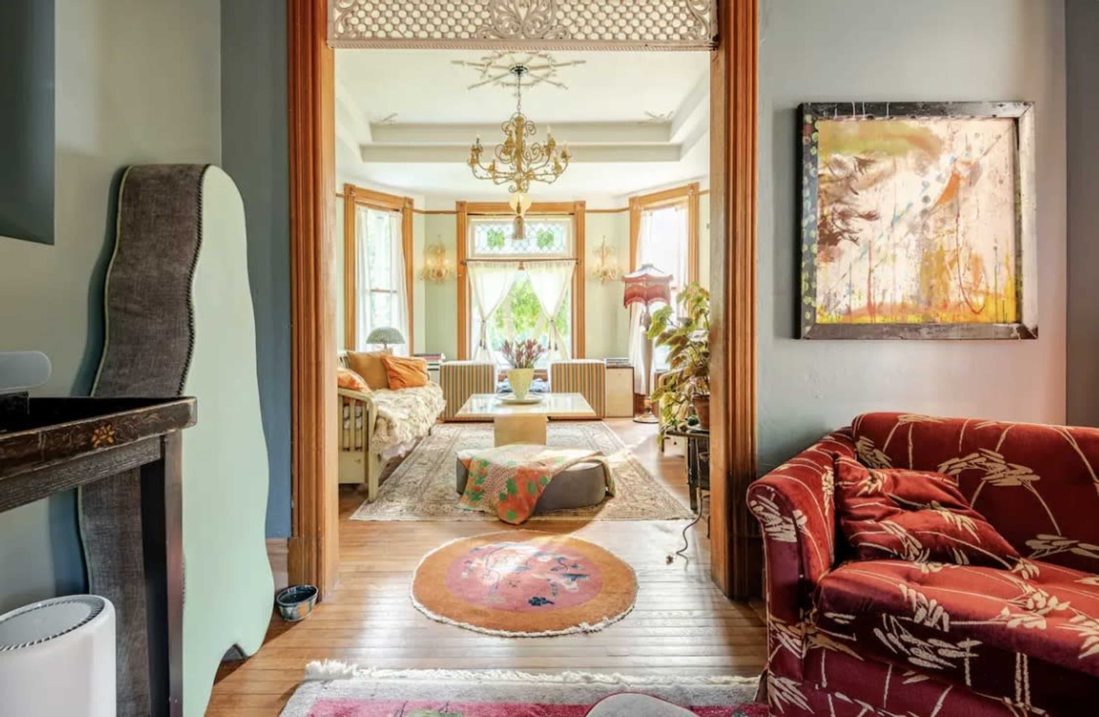 The image shows a beautifully decorated interior space featuring a living room with large windows, colorful furniture, and decorative accents.