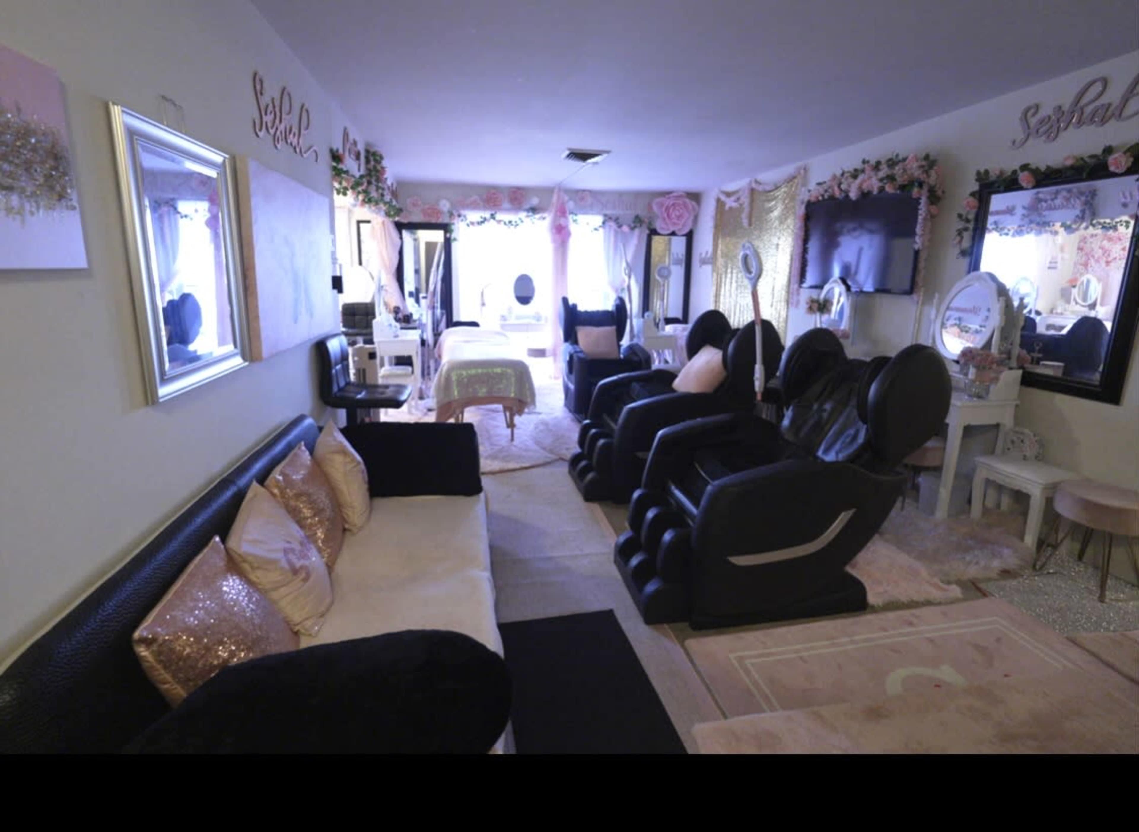 A beauty salon interior with black and white furniture, multiple styling chairs, and decorative elements like mirrors and floral accents.