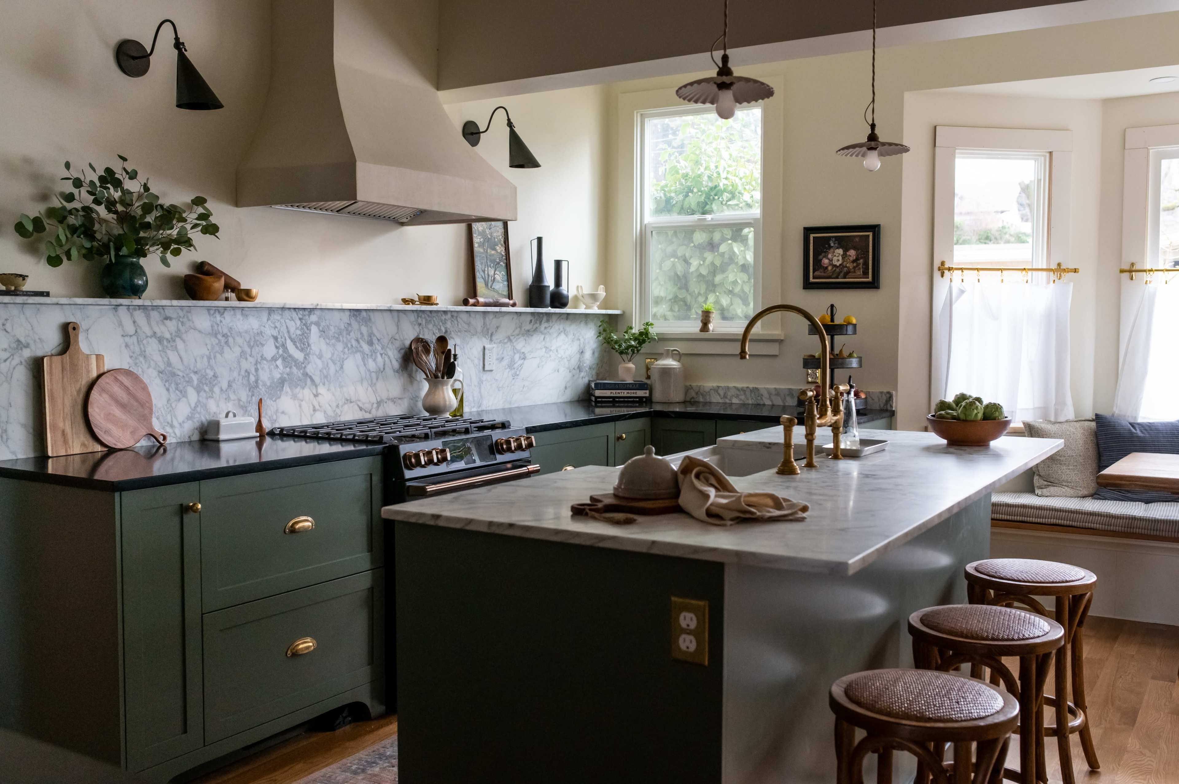 The kitchen features a marble countertop, green cabinetry, a large stove, and a window seat with natural light.