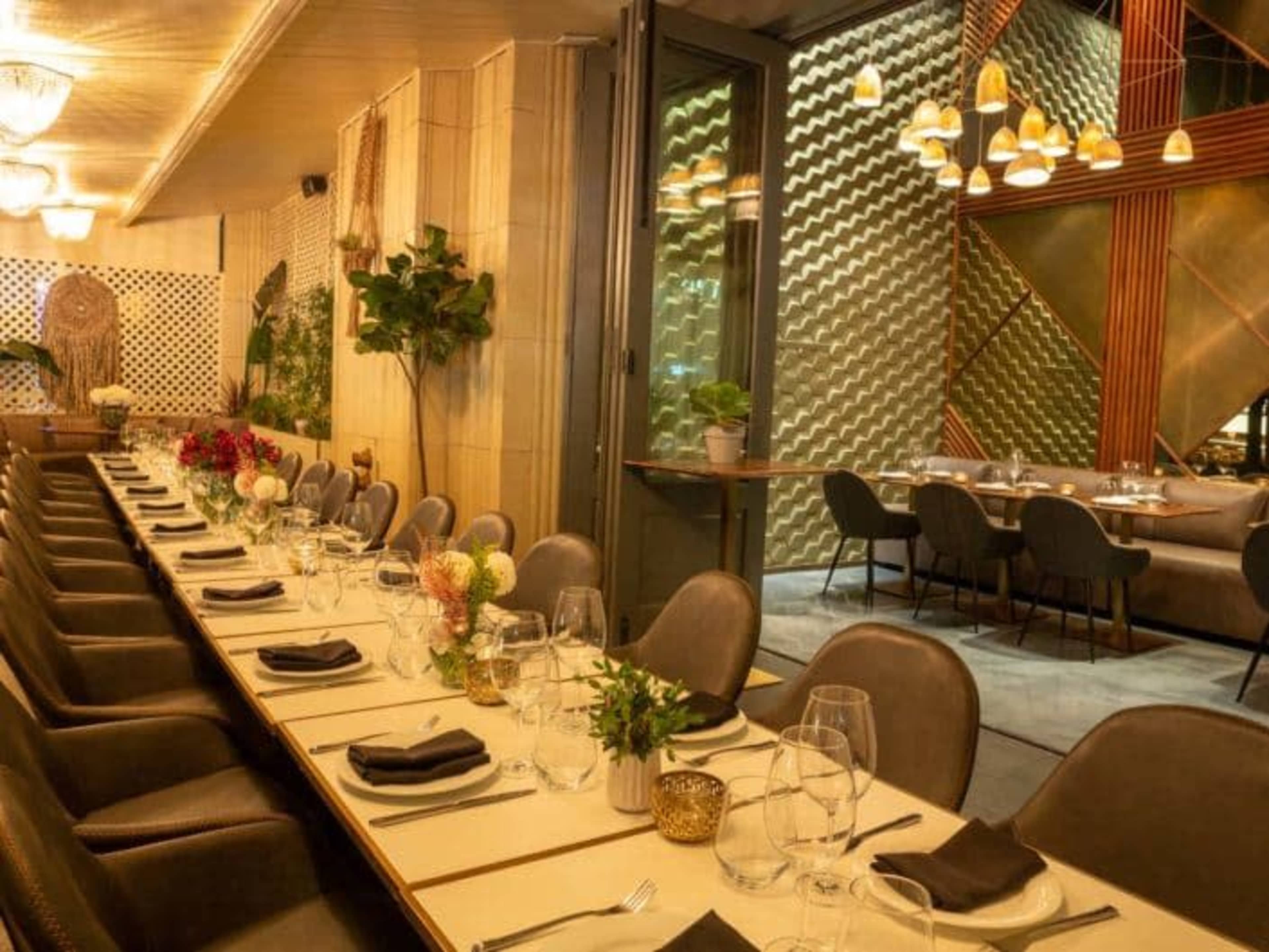 A dining area in a restaurant with a long, elegantly set table and a cozy seating arrangement.