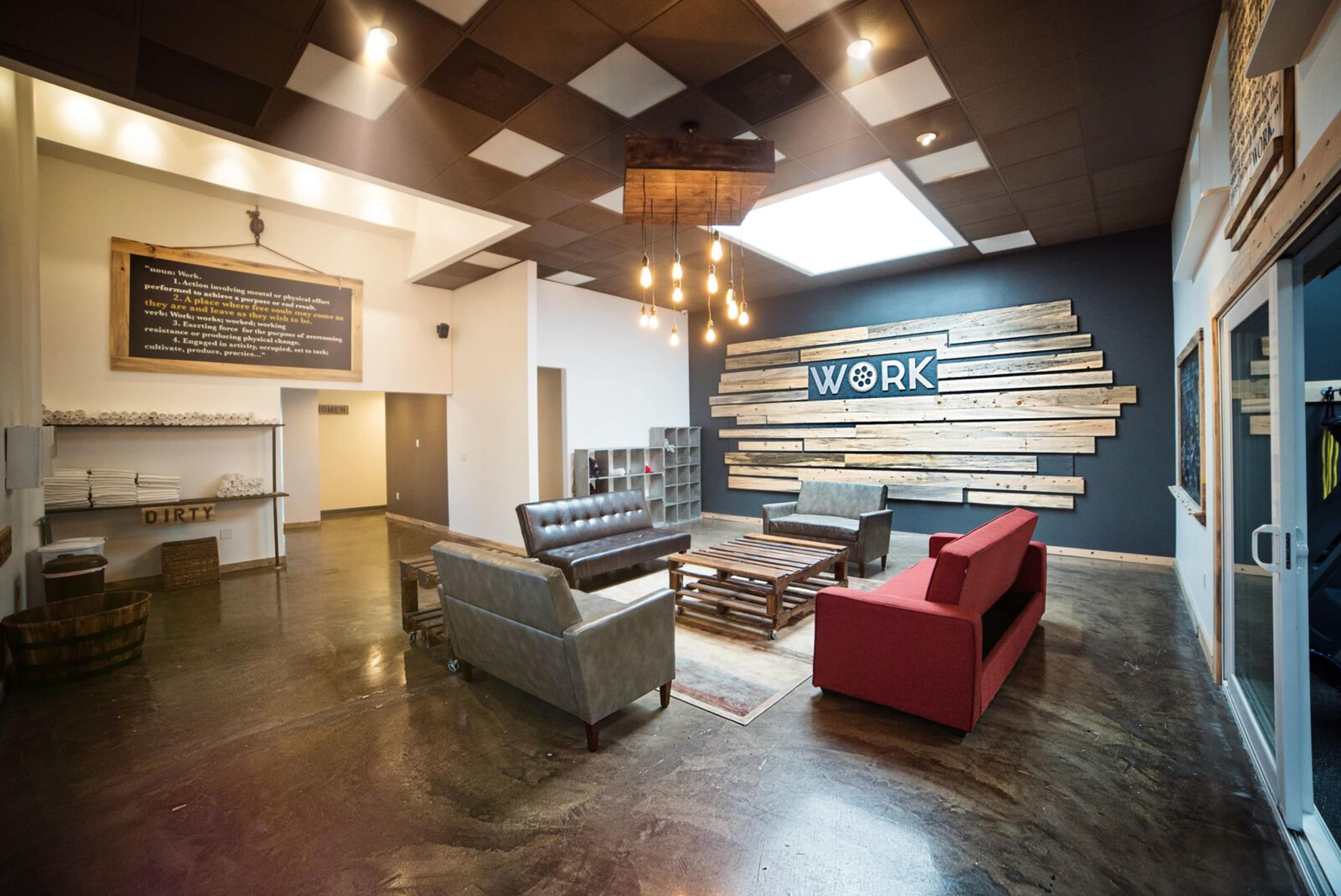 A spacious interior with a seating area featuring a mix of couches and a coffee table, along with a decorative wall that displays the word "WORK" in bold letters.