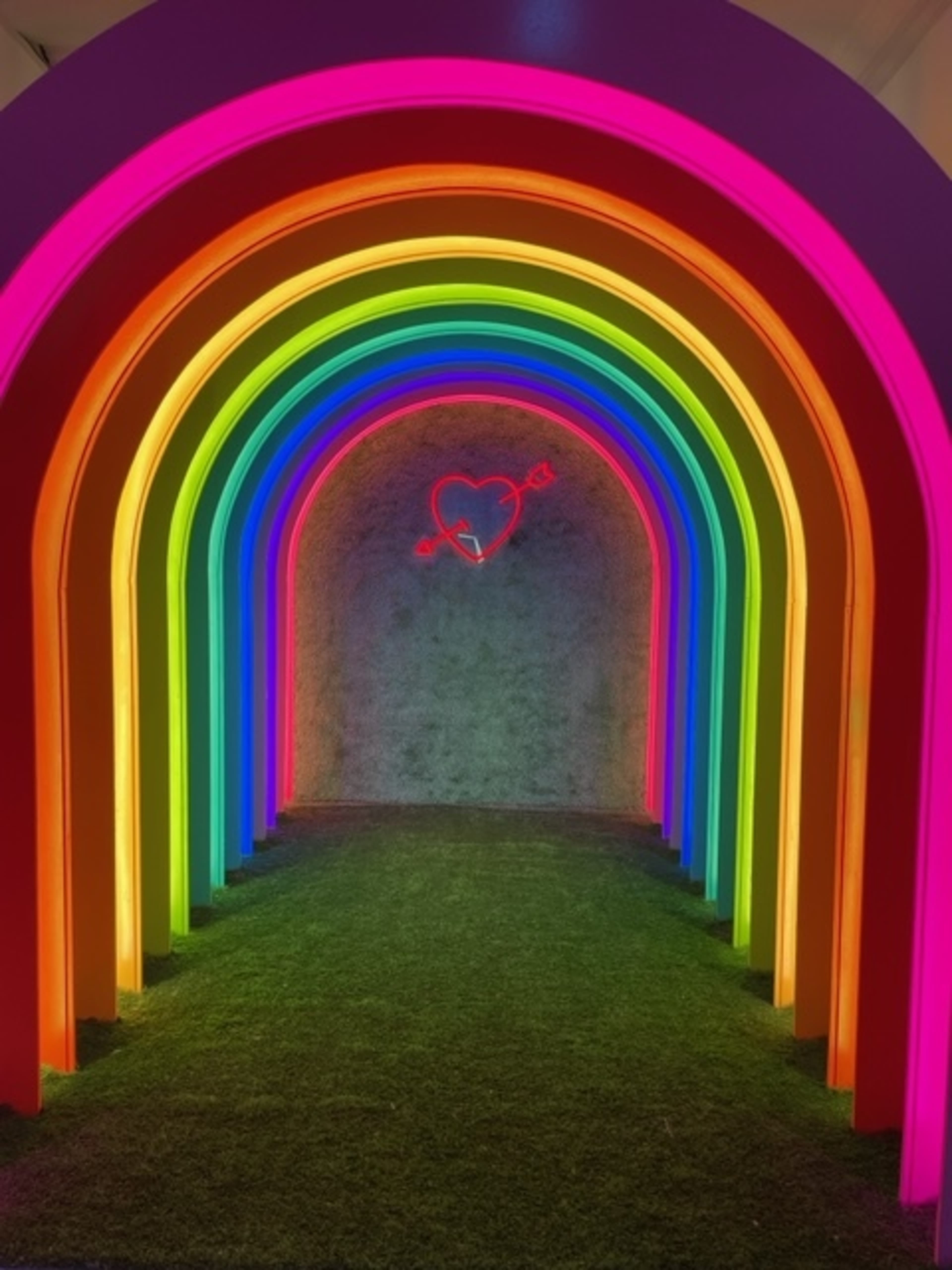 A brightly lit rainbow archway set against a grassy backdrop.