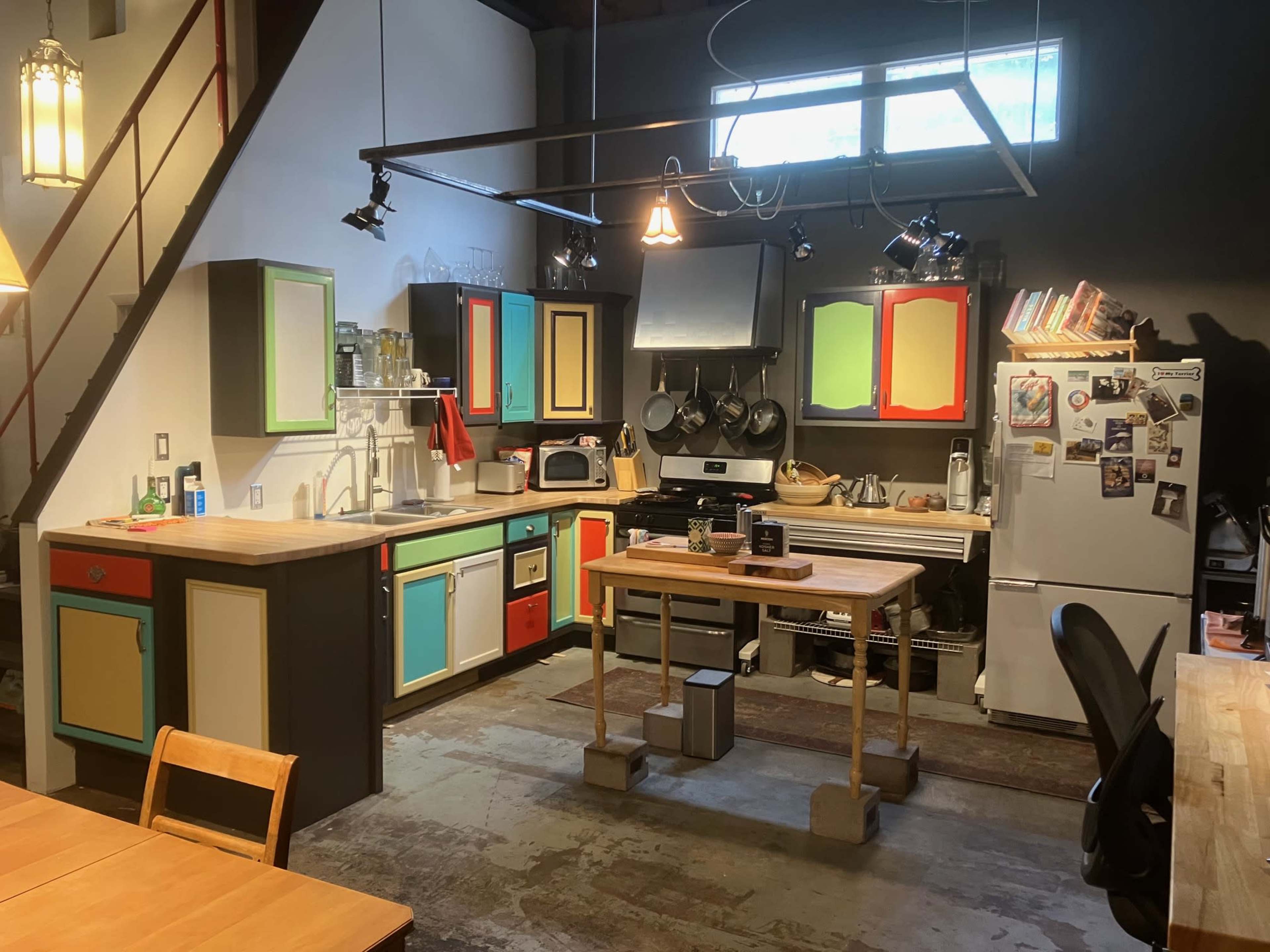 A colorful kitchen with various appliances, a central wooden island, and a blend of open shelving and cabinets.