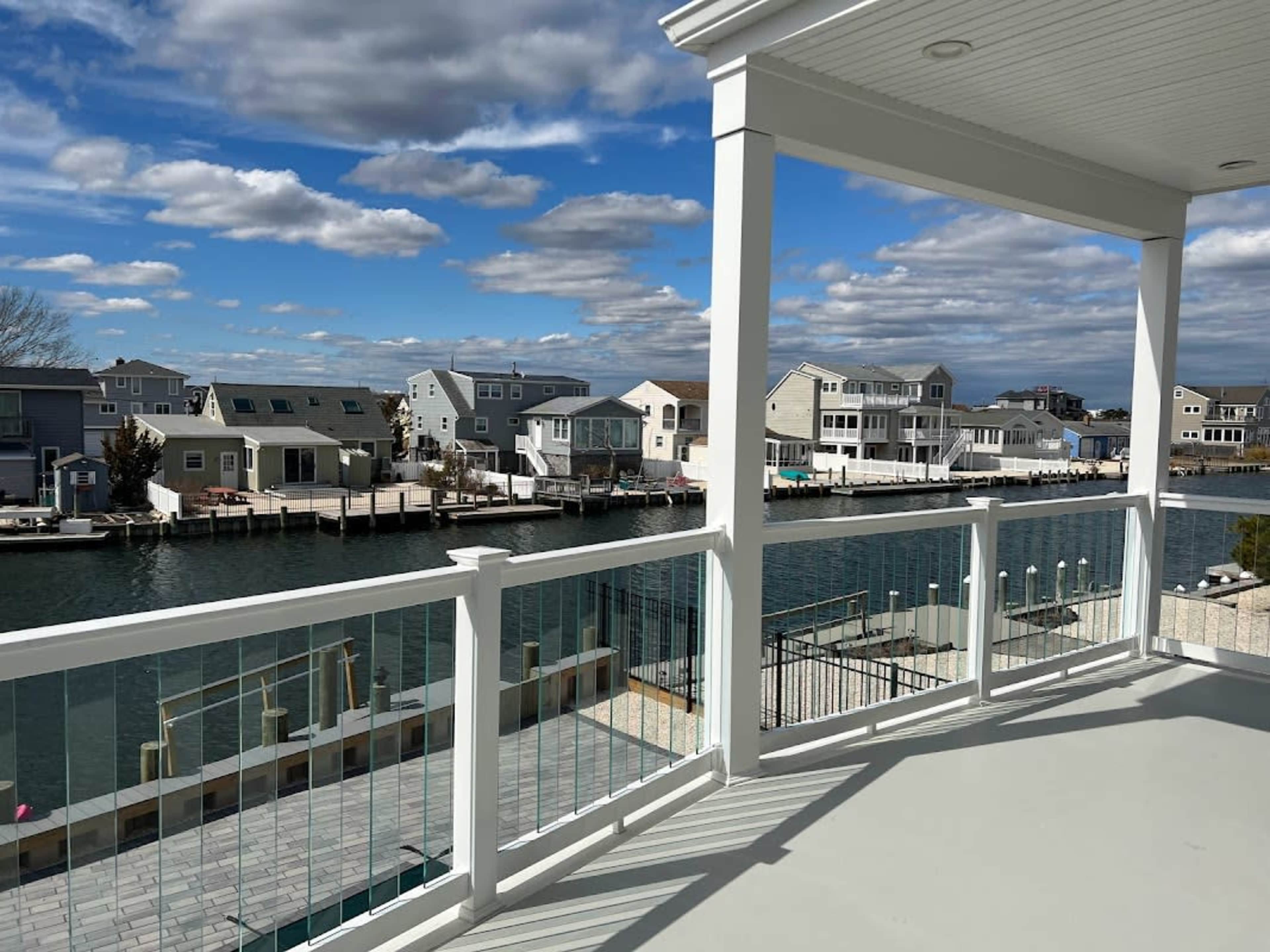 The image shows a balcony overlooking a canal lined with houses on both sides under a cloudy sky.