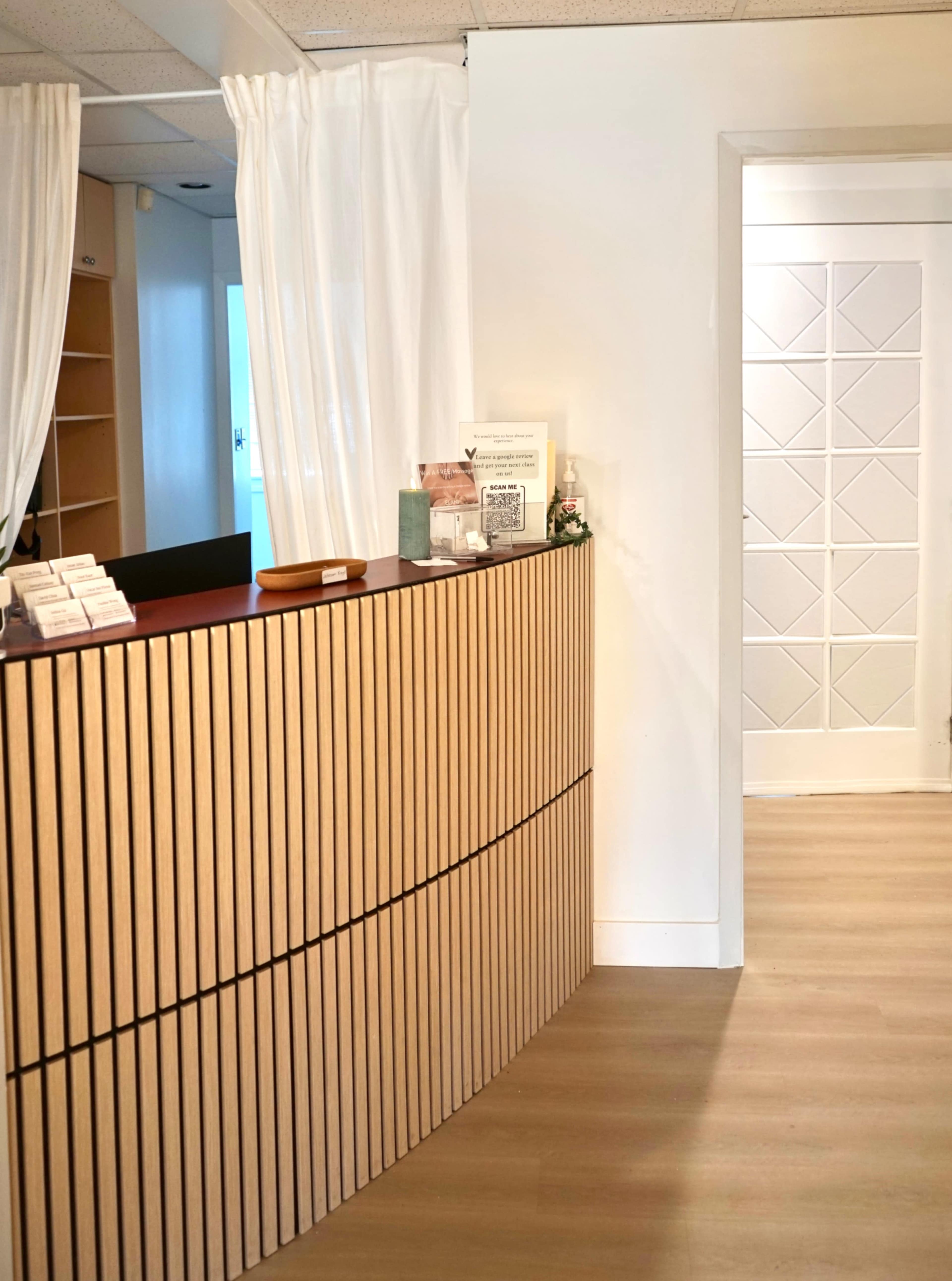 The image shows a reception area with a curved wooden front desk and a hallway leading to a door in the background.