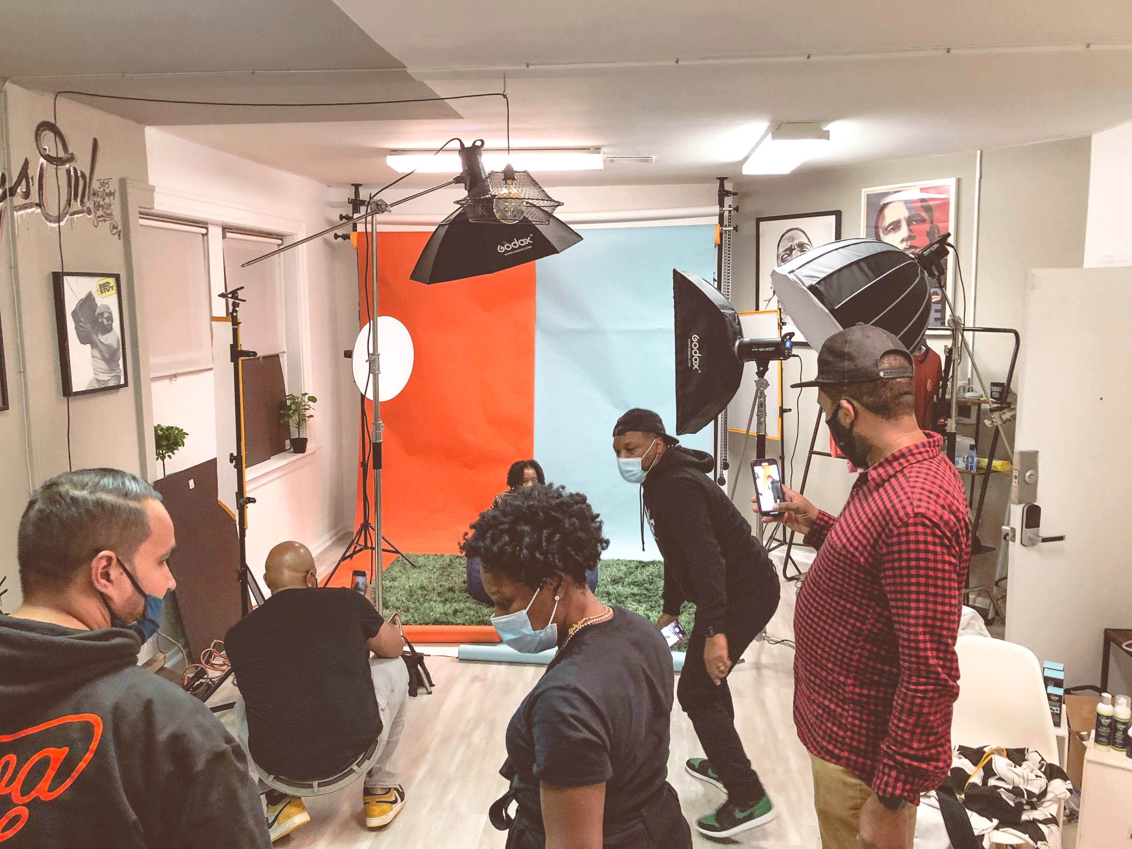 A group of individuals set up a photoshoot in a studio with a colorful backdrop and multiple lighting equipment.