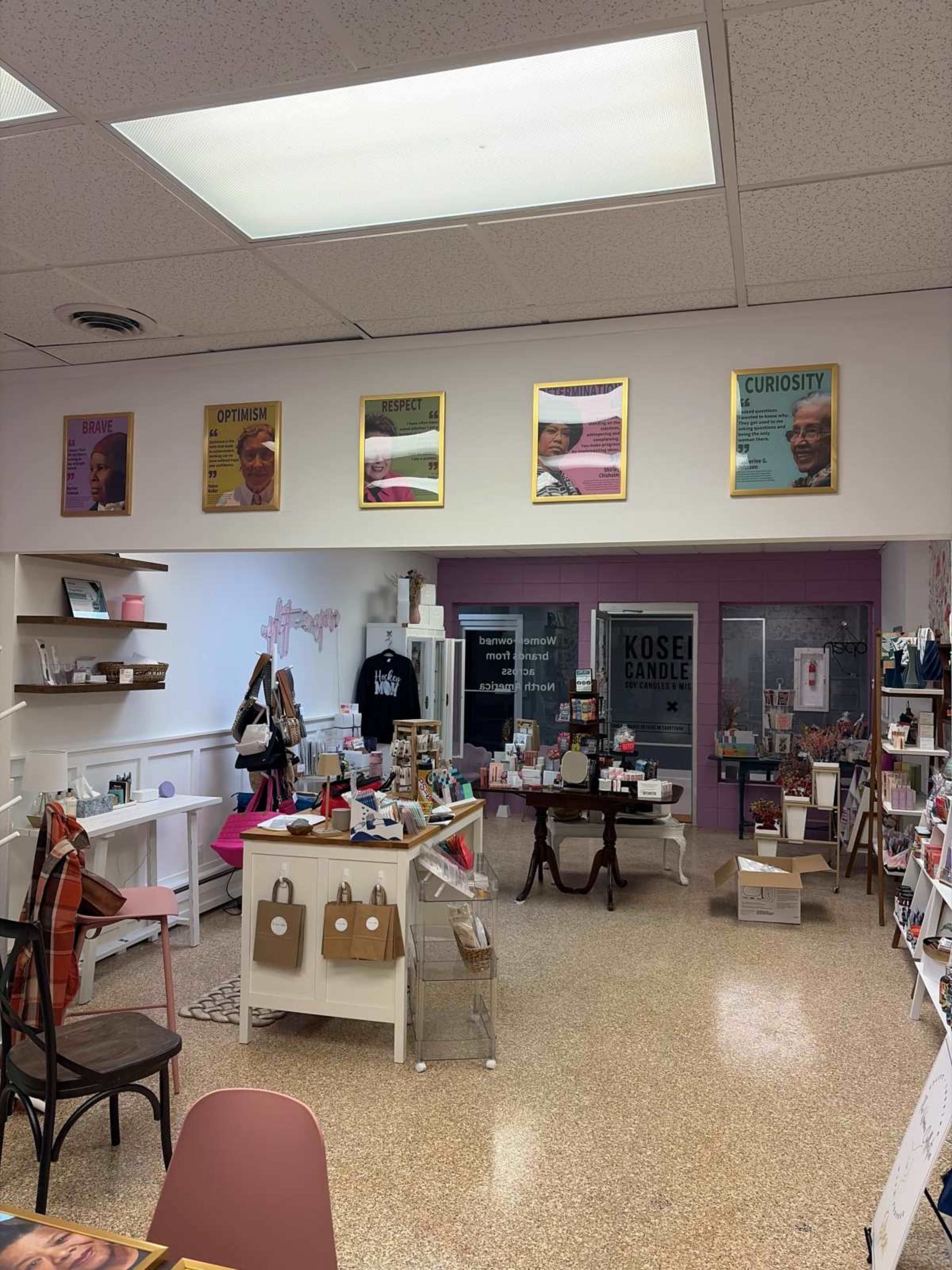 The image shows a retail space featuring shelves with various products, a centered table, and colorful motivational posters on the walls.