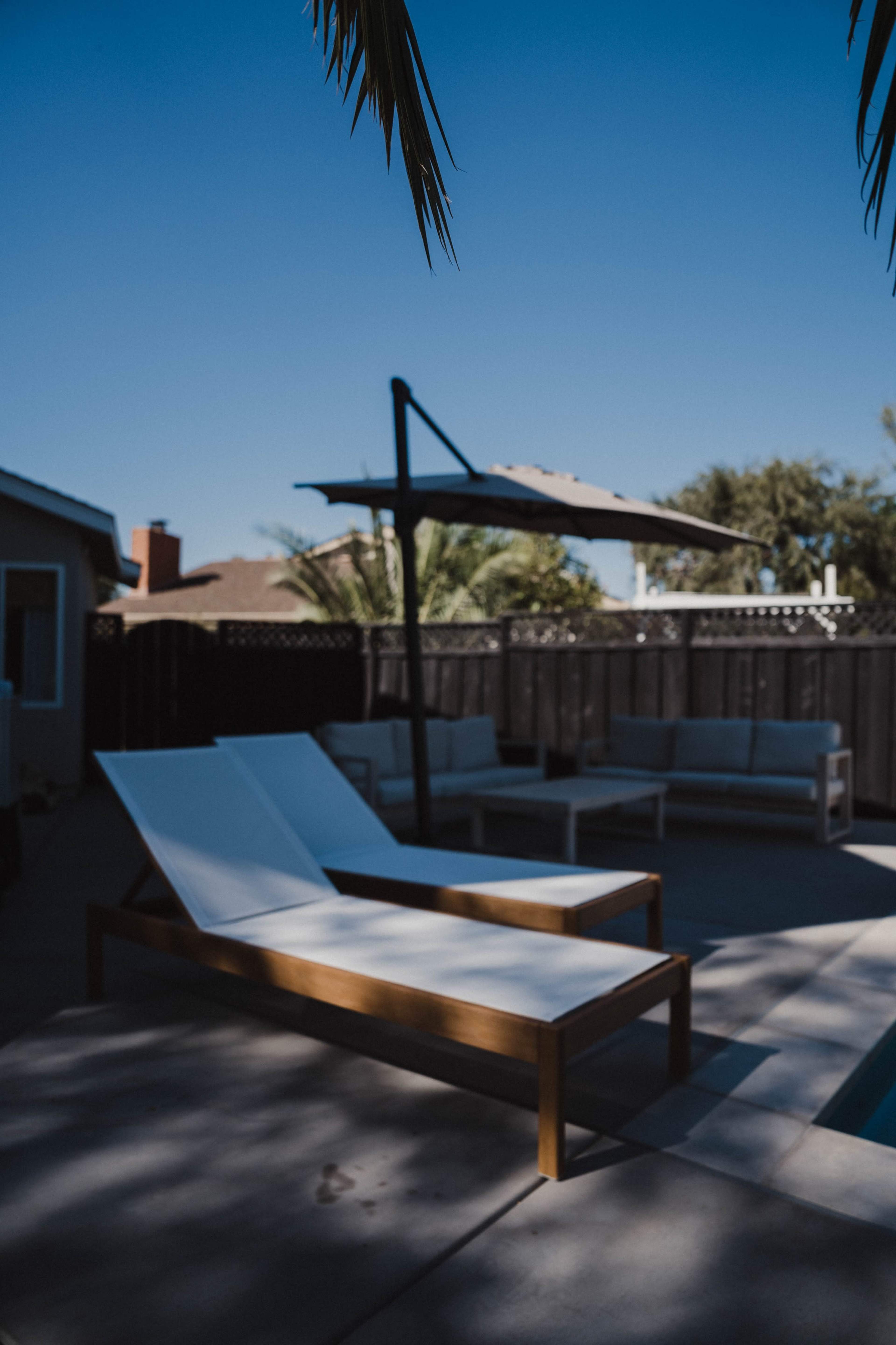 A poolside area with two white lounge chairs and a shaded seating area in the background.