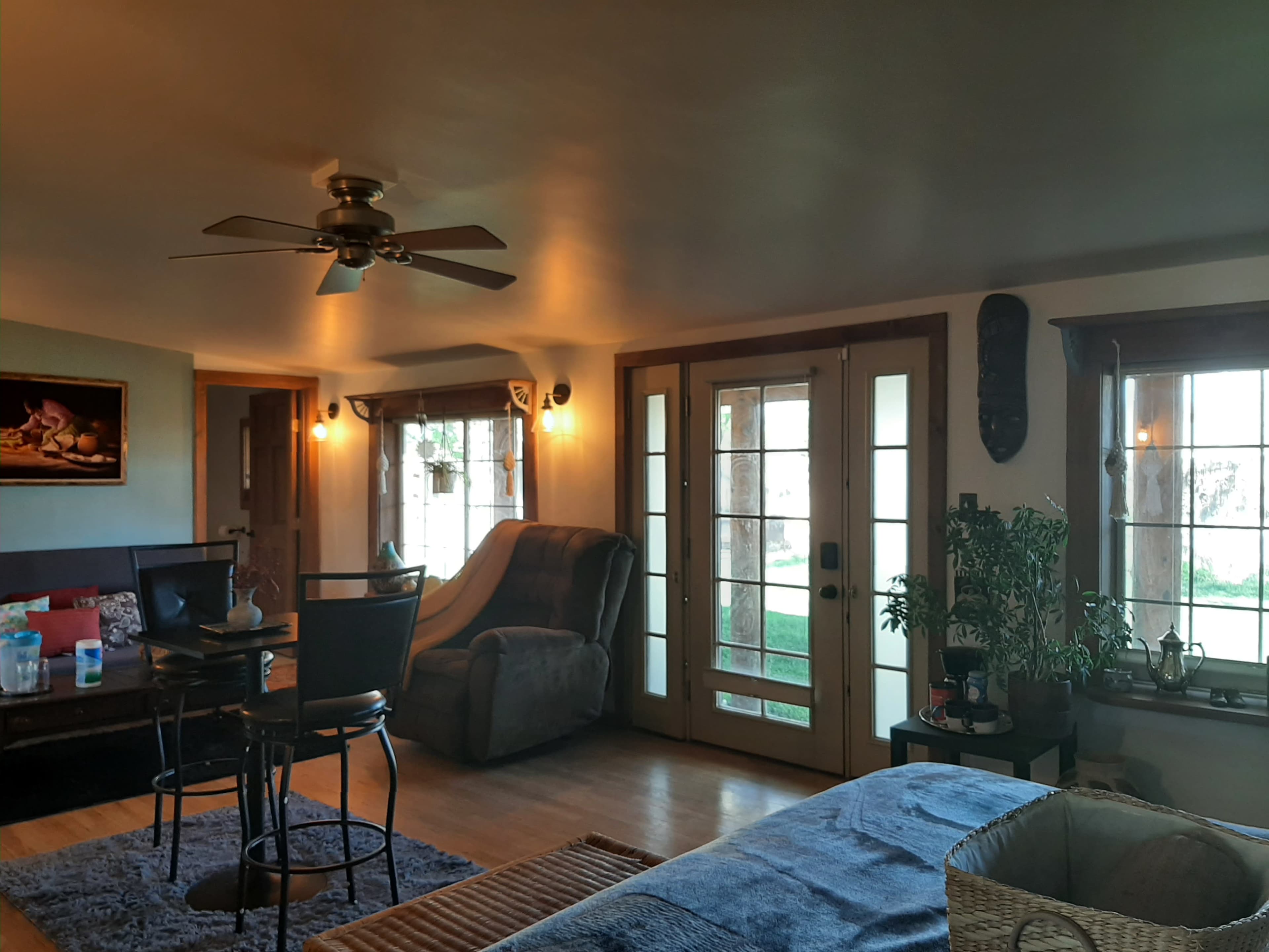 A living area with a ceiling fan, a dining table with chairs, a reclined chair, and French doors leading to an outdoor space.