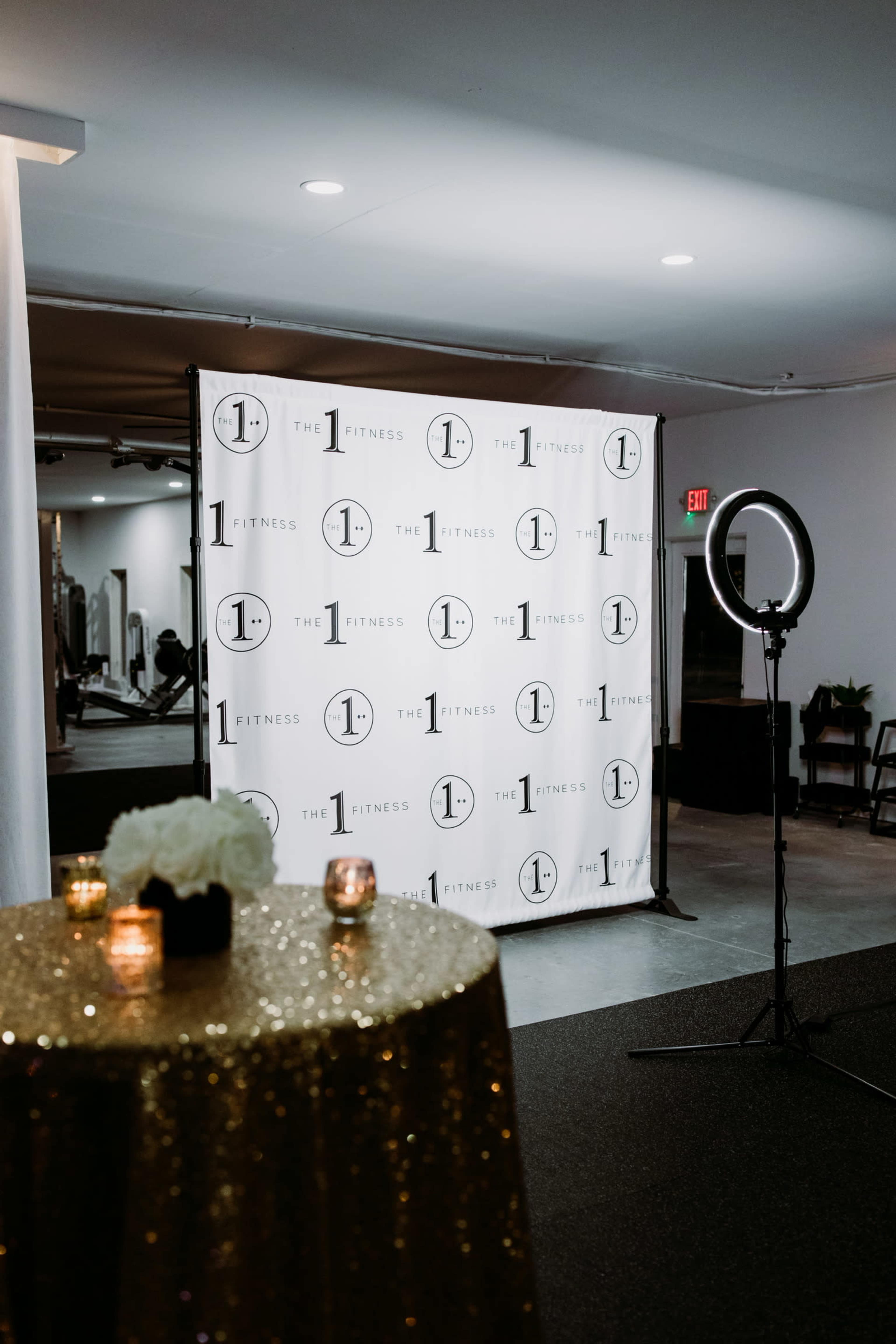 A decorated area features a shimmering table, a circular light, and a backdrop with the logo of a fitness brand.