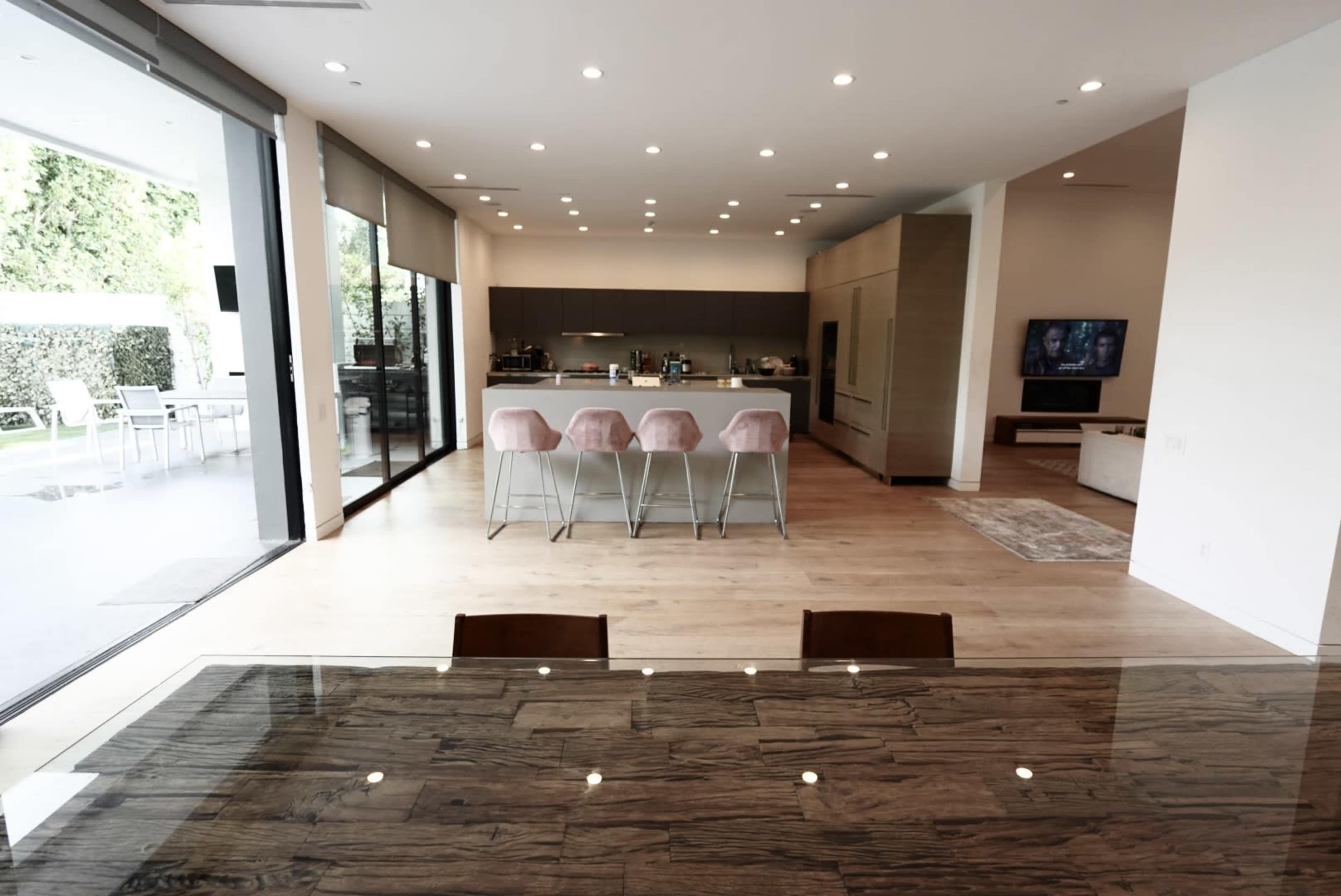 A modern, open-concept dining area leading into a spacious kitchen with bar seating and large glass doors opening to an outdoor patio.
