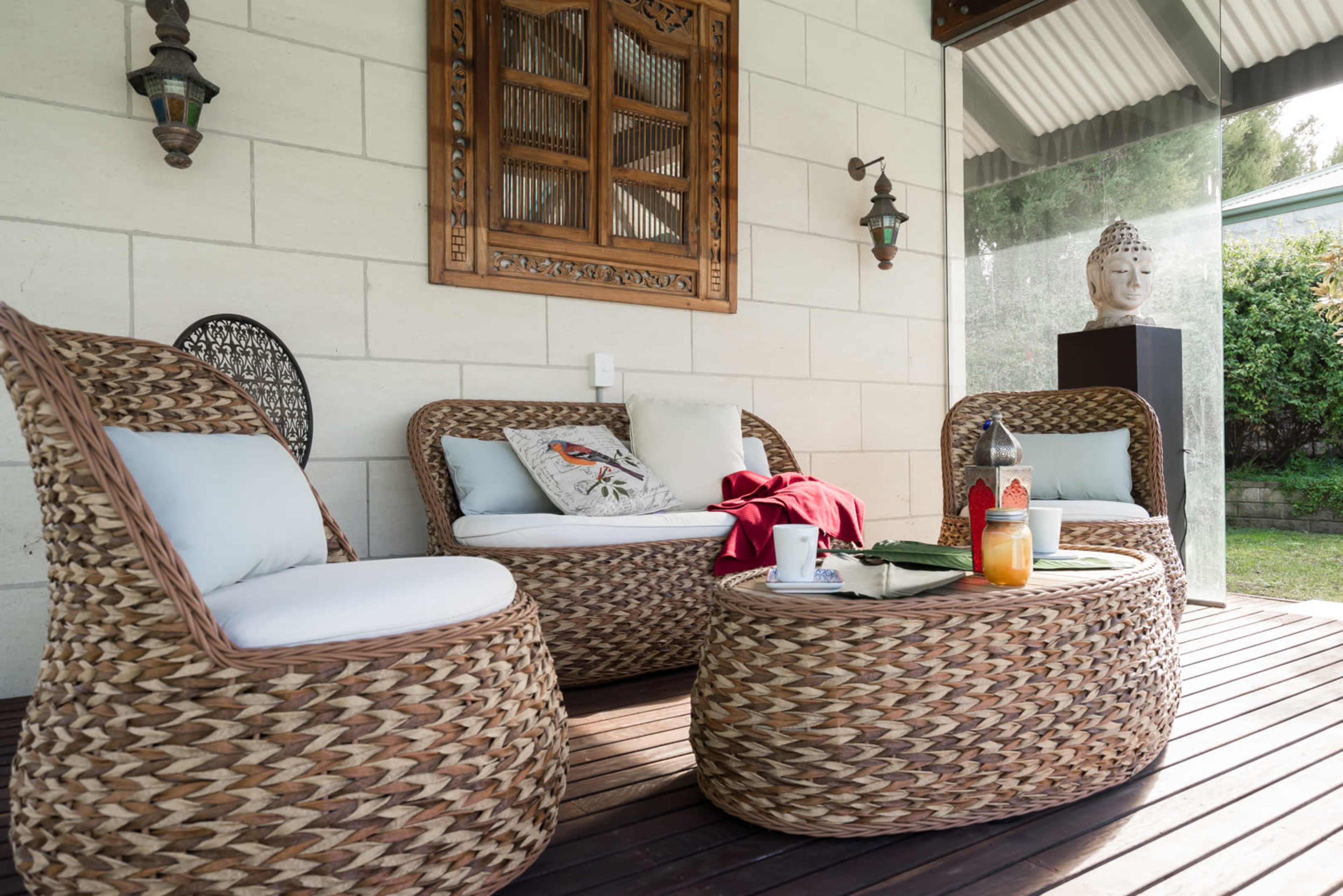 A cozy outdoor seating area featuring woven furniture and a decorative wooden wall hanging.