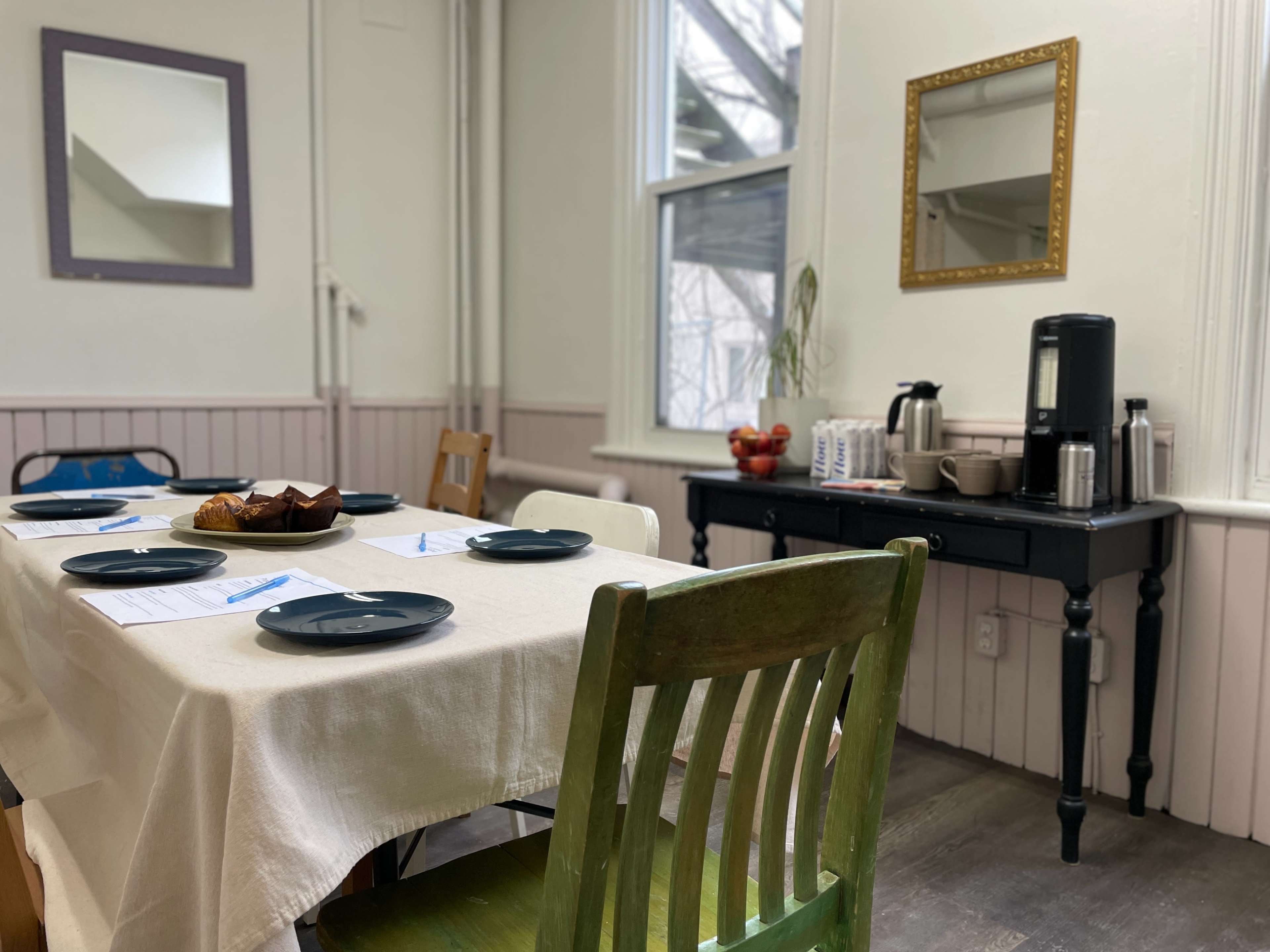 A dining area features a table set with blue plates, a white tablecloth, and a side counter with a coffee maker and snacks.