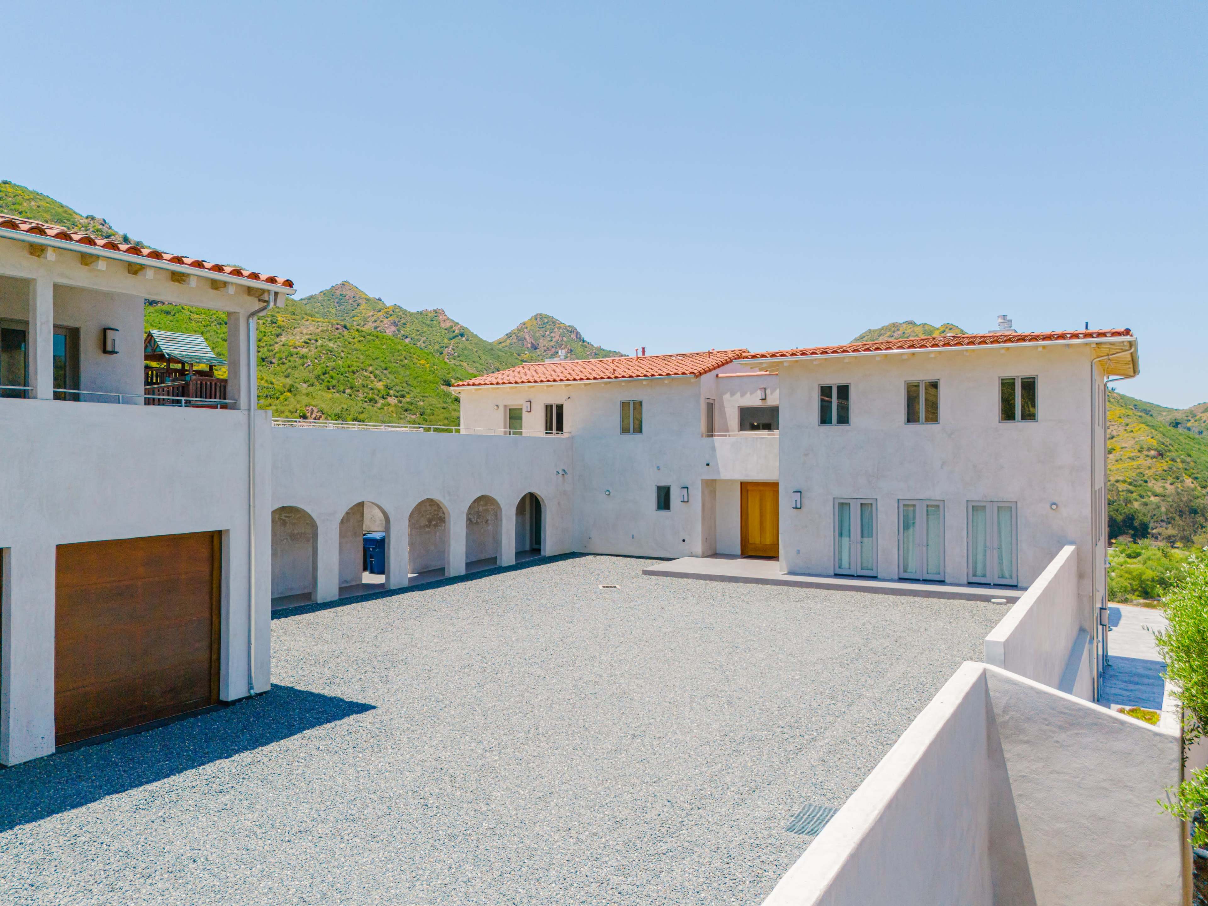 A modern house with a rectangular courtyard surrounded by mountains is depicted.