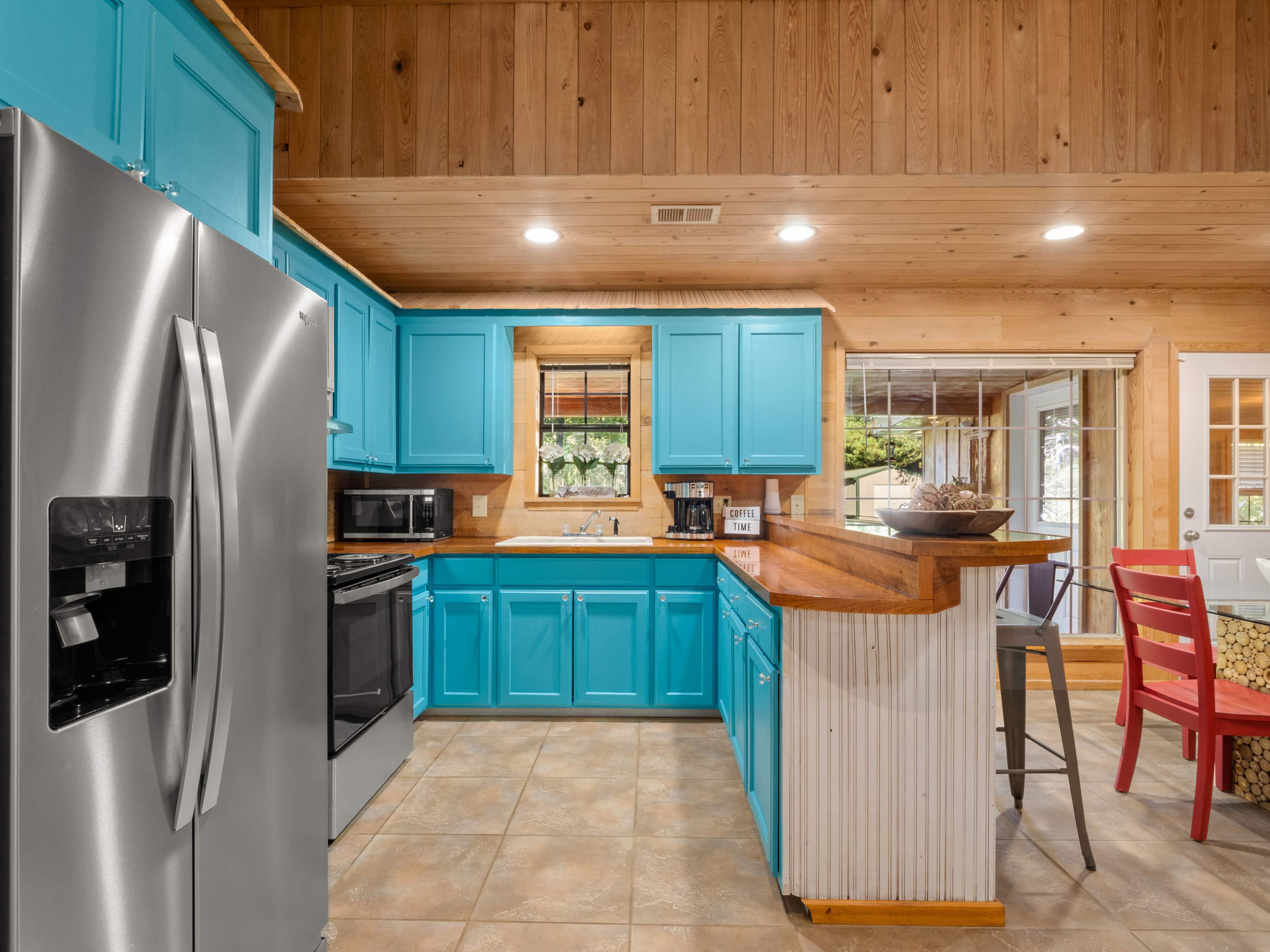 A kitchen with bright blue cabinets, stainless steel appliances, and a wooden countertop.