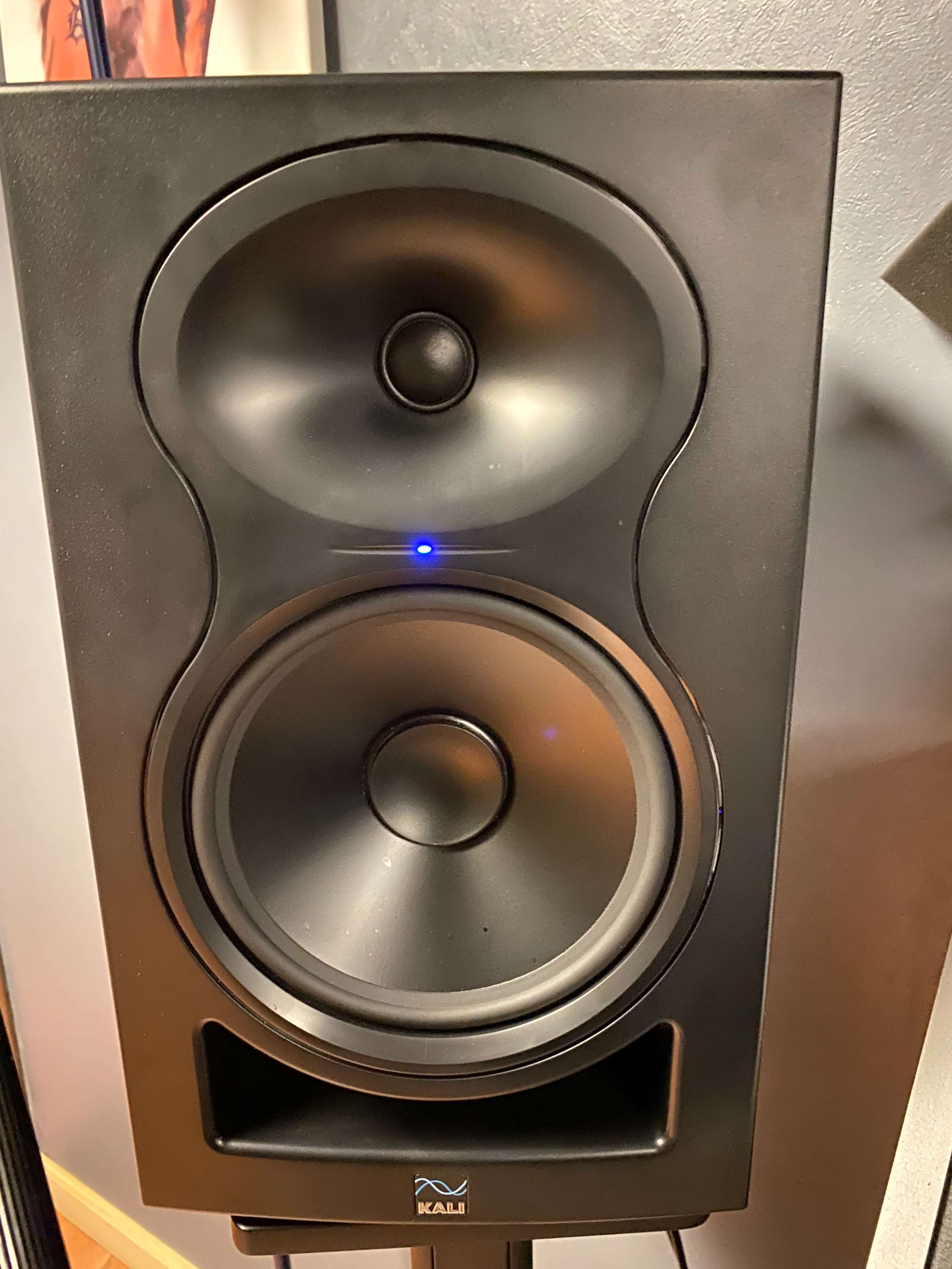 A black speaker with two round drivers and a blue LED indicator light.