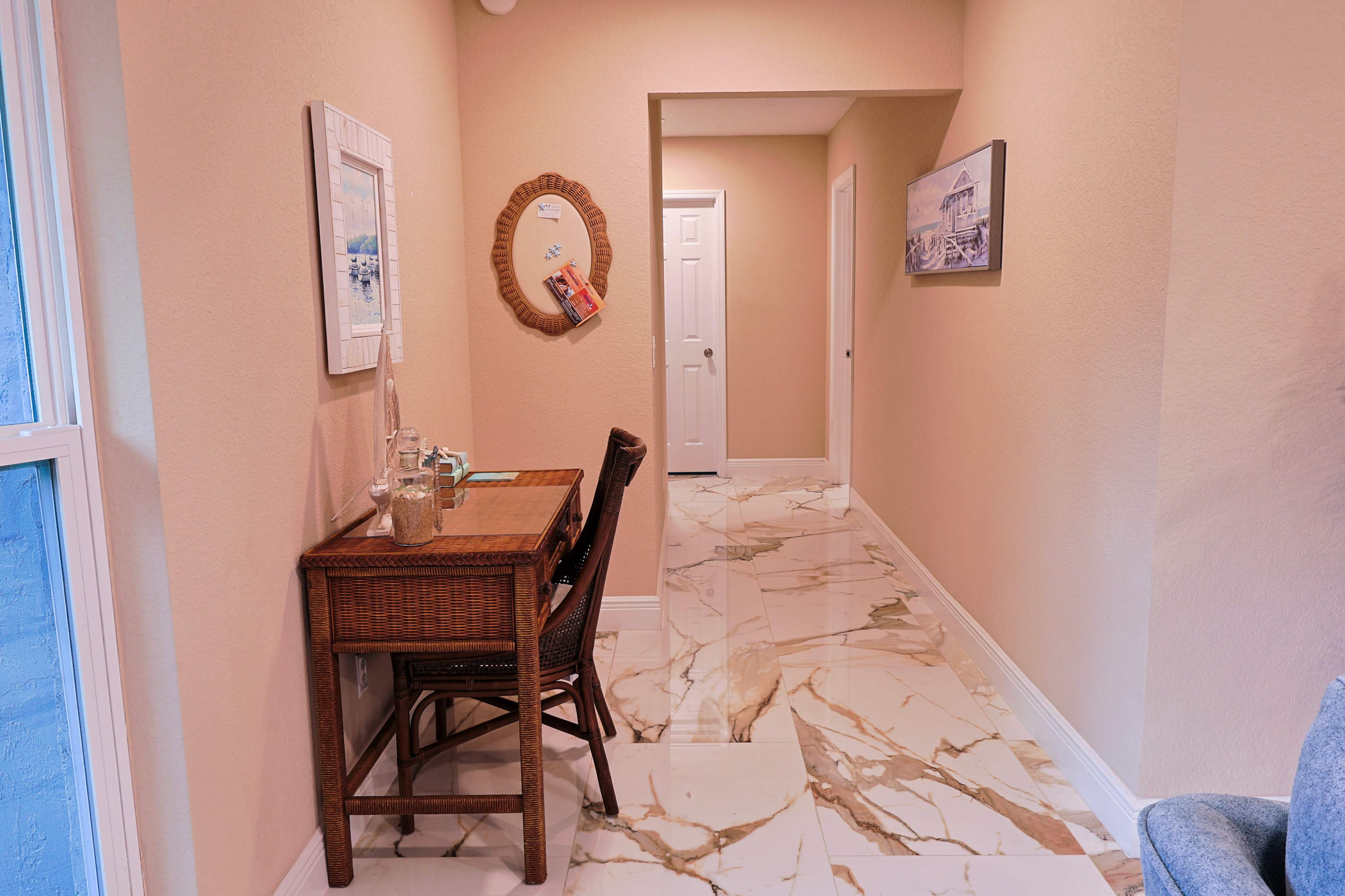 The image shows a narrow hallway with light-colored walls, a small wooden table with a chair, and marble-like flooring.