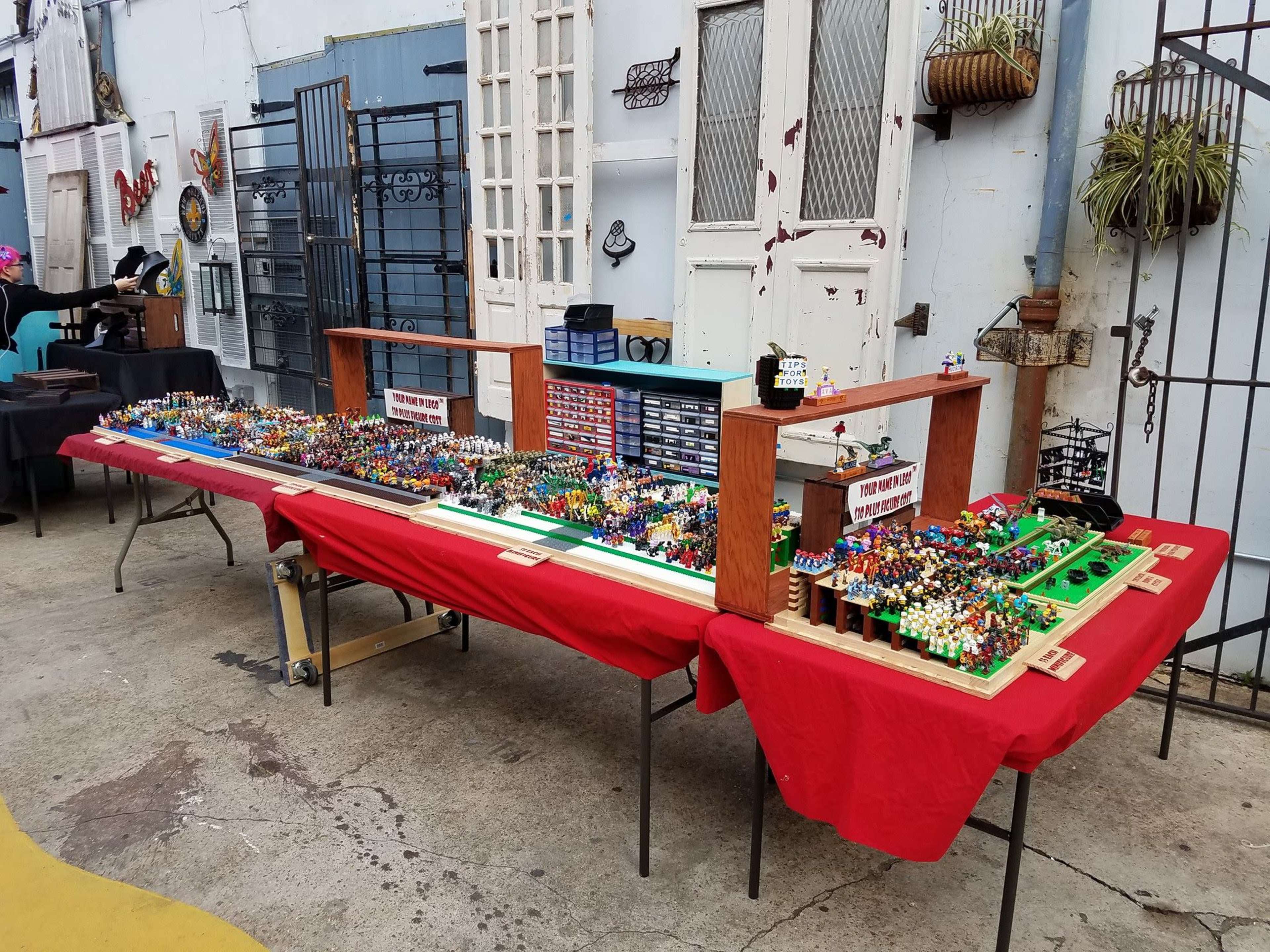 A table with red tablecloths displays a variety of colorful miniature figurines and collectibles arranged neatly in rows.