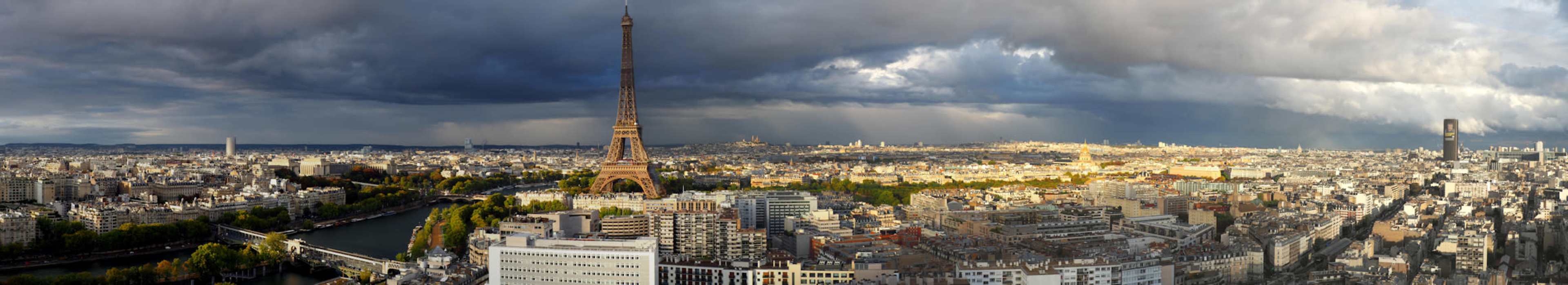 A panoramic view of Paris features the Eiffel Tower prominently against a skyline dotted with buildings and a river.